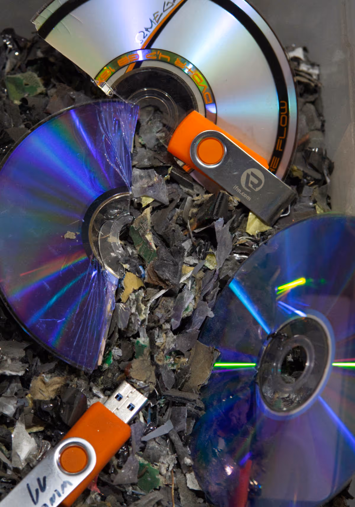 Zerbrochene CDs und USB-Sticks liegen auf geschreddertem Material
