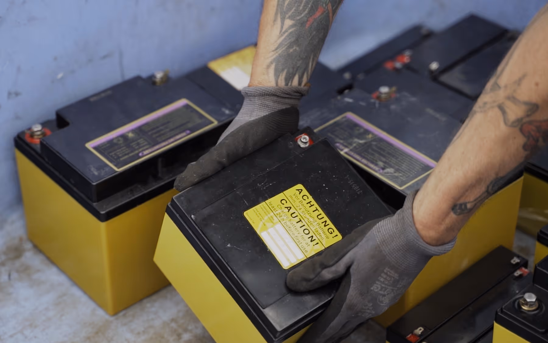 Zum Entsorgen legt jemand eine große Batterie in eine Box mit vielen anderen Batterien.