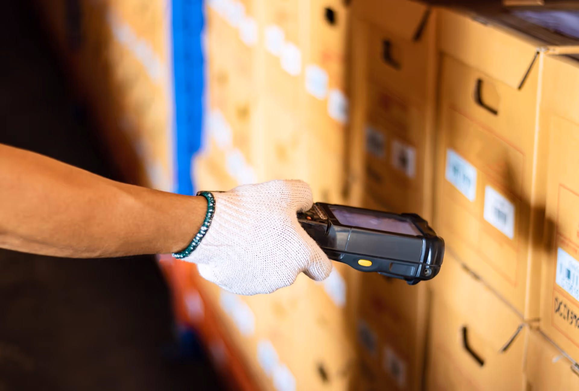 Jemand hält einen Scanner vor eine Box in einem Boxenlager.