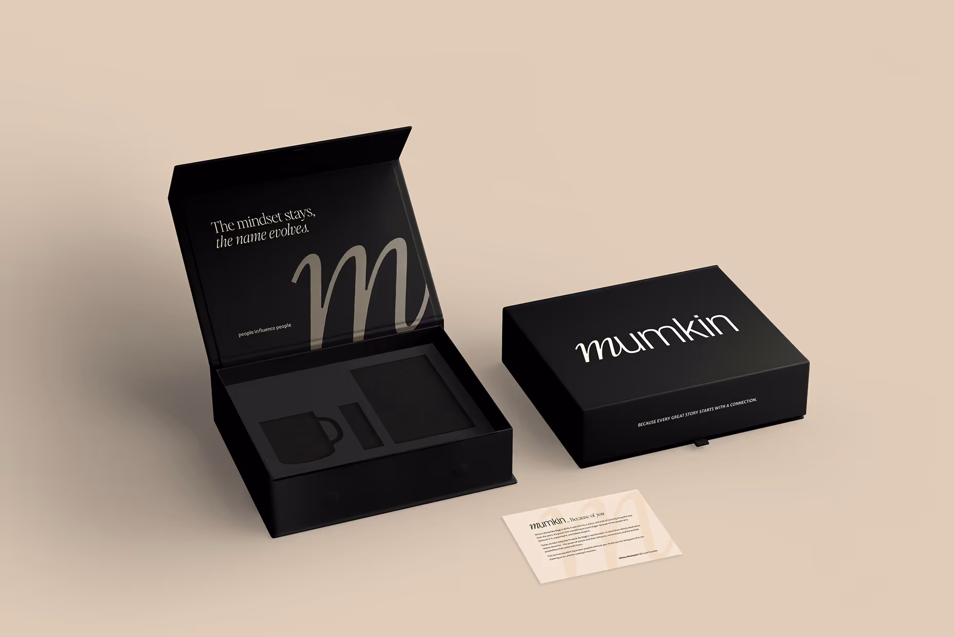 Black branded packaging box with the word 'mumkin', one box open showing a cup and other item slots, and a card with a message on a beige surface.