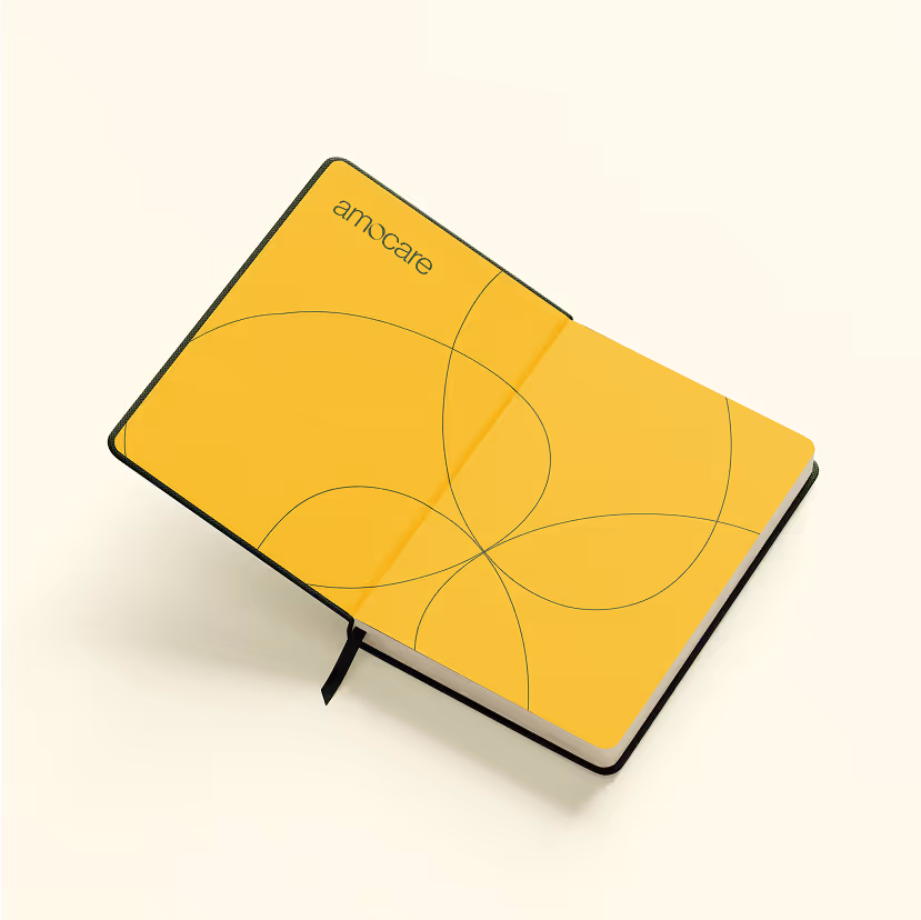 Open notebook with yellow pages featuring thin black intersecting curved lines and the word 'amocare' in the top left corner.