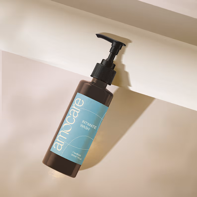 Brown pump bottle of Amocare intimate wash with a light blue label on a beige and cream background.