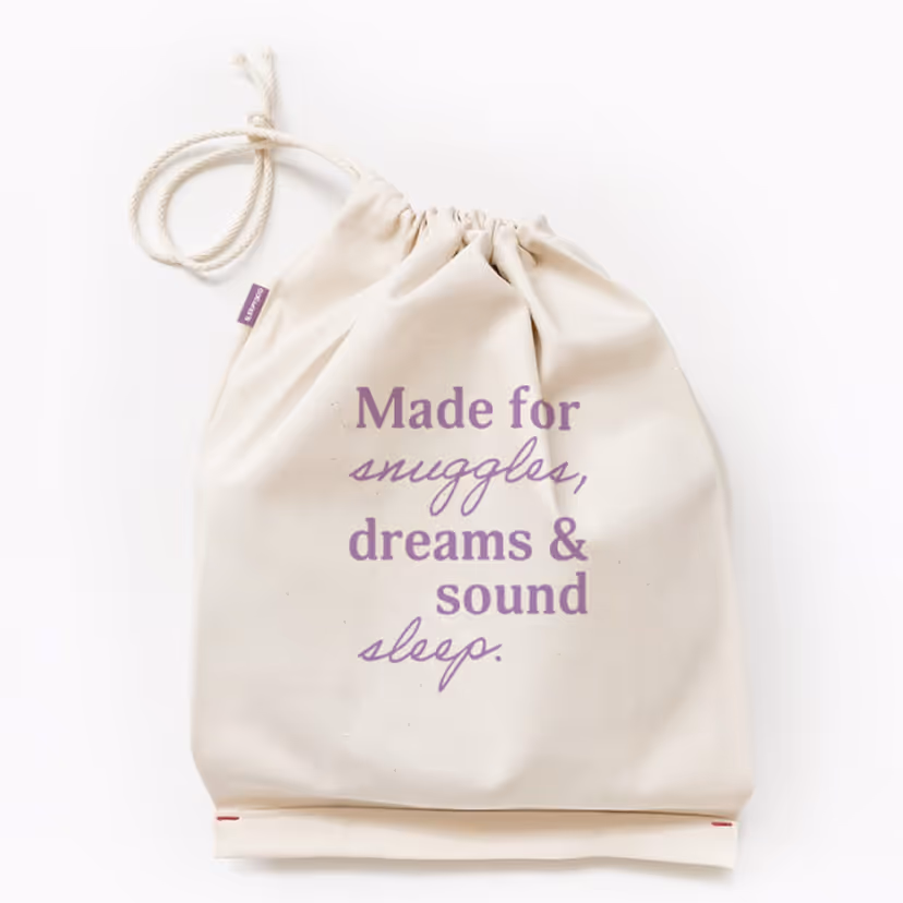 Natural-colored drawstring bag with purple text reading 'Made for snuggles, dreams & sound sleep.'