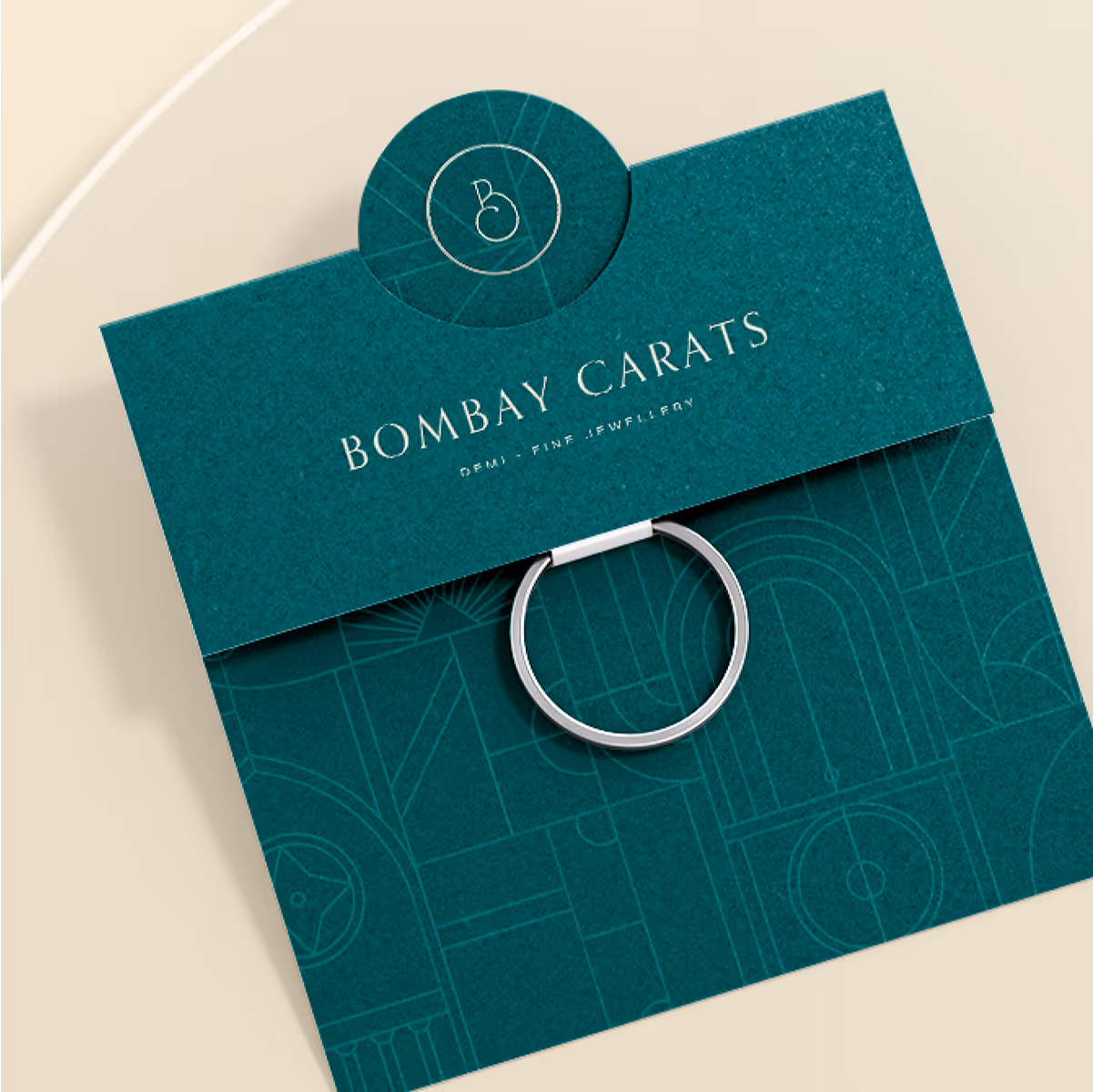 Silver ring on a teal Bombay Carats jewelry card with geometric pattern and logo.