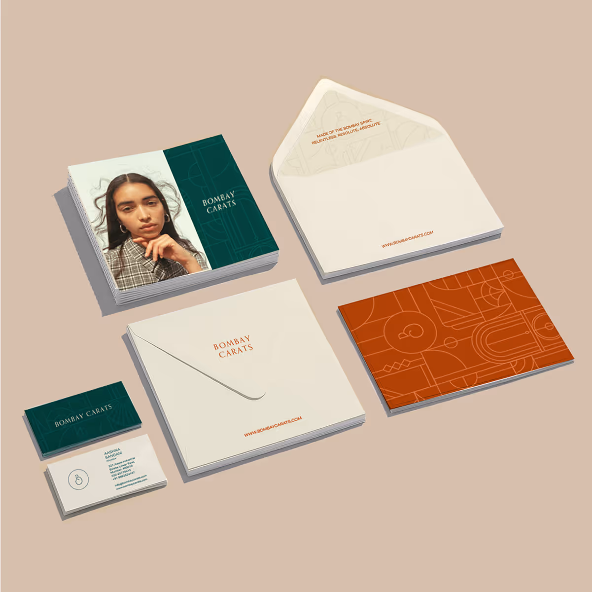 Flat lay of Bombay Carats branded stationery including business cards, envelopes, and promotional cards featuring minimalist designs and a woman's portrait.