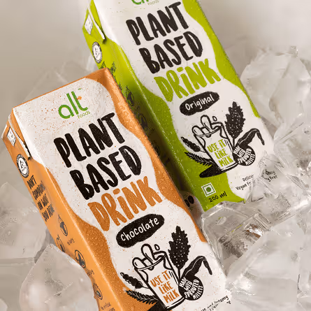Two cartons of All Food plant-based drink, one chocolate and one original flavor, placed on ice cubes.