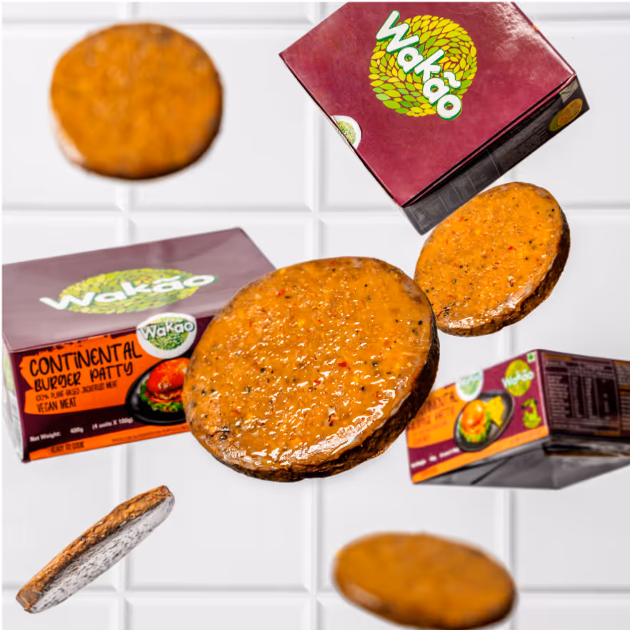 Multiple vegan burger patties floating alongside Wakao Continental Burger Patty boxes on a white tiled background.
