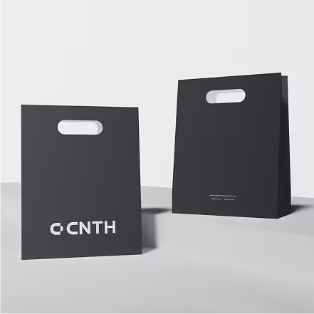 Two black paper shopping bags with die-cut handles, one showing the front with a white CNTN logo and the other showing the back with small white text.