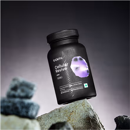 Black supplement bottle labeled Cellular Revive with a purple cell image, balanced on a rock against a blurred background.