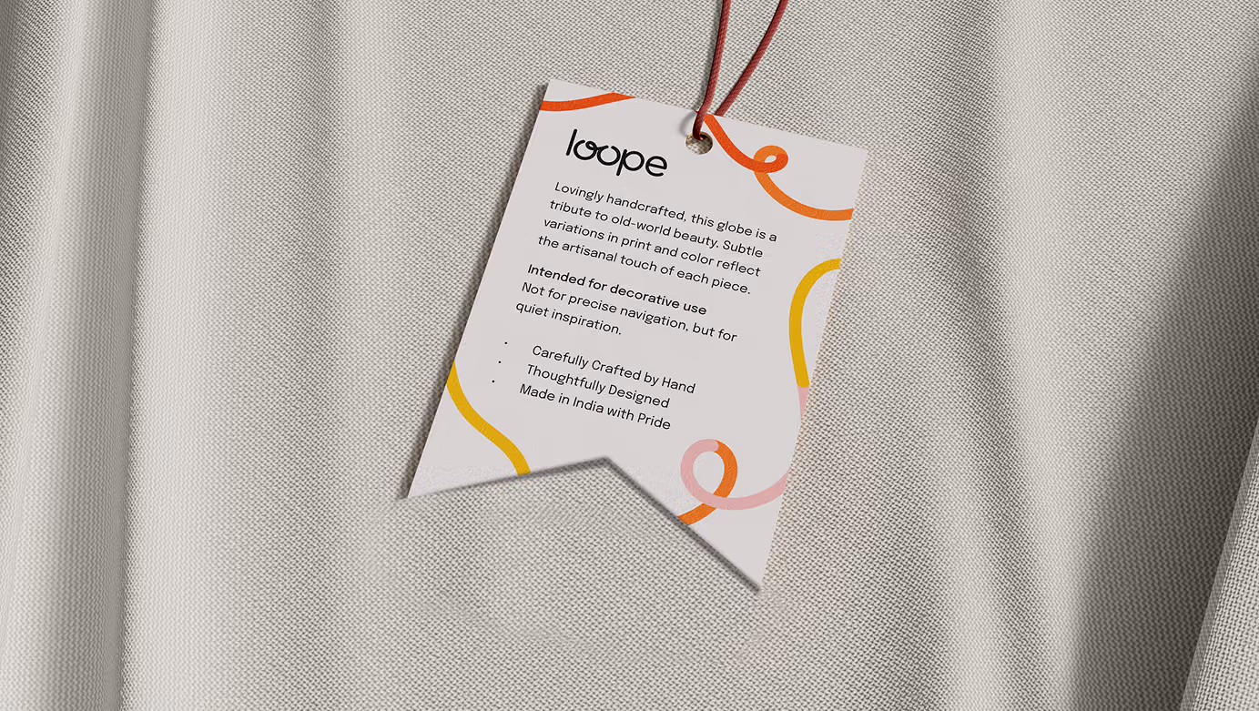 Tag attached to fabric with text describing a handcrafted decorative globe by loop, highlighting artisanal background and made in India.