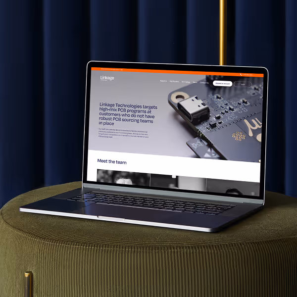 Laptop displaying Linkage Technologies website focusing on high-mix PCB programs, placed on a green round textured surface with dark curtains in the background.