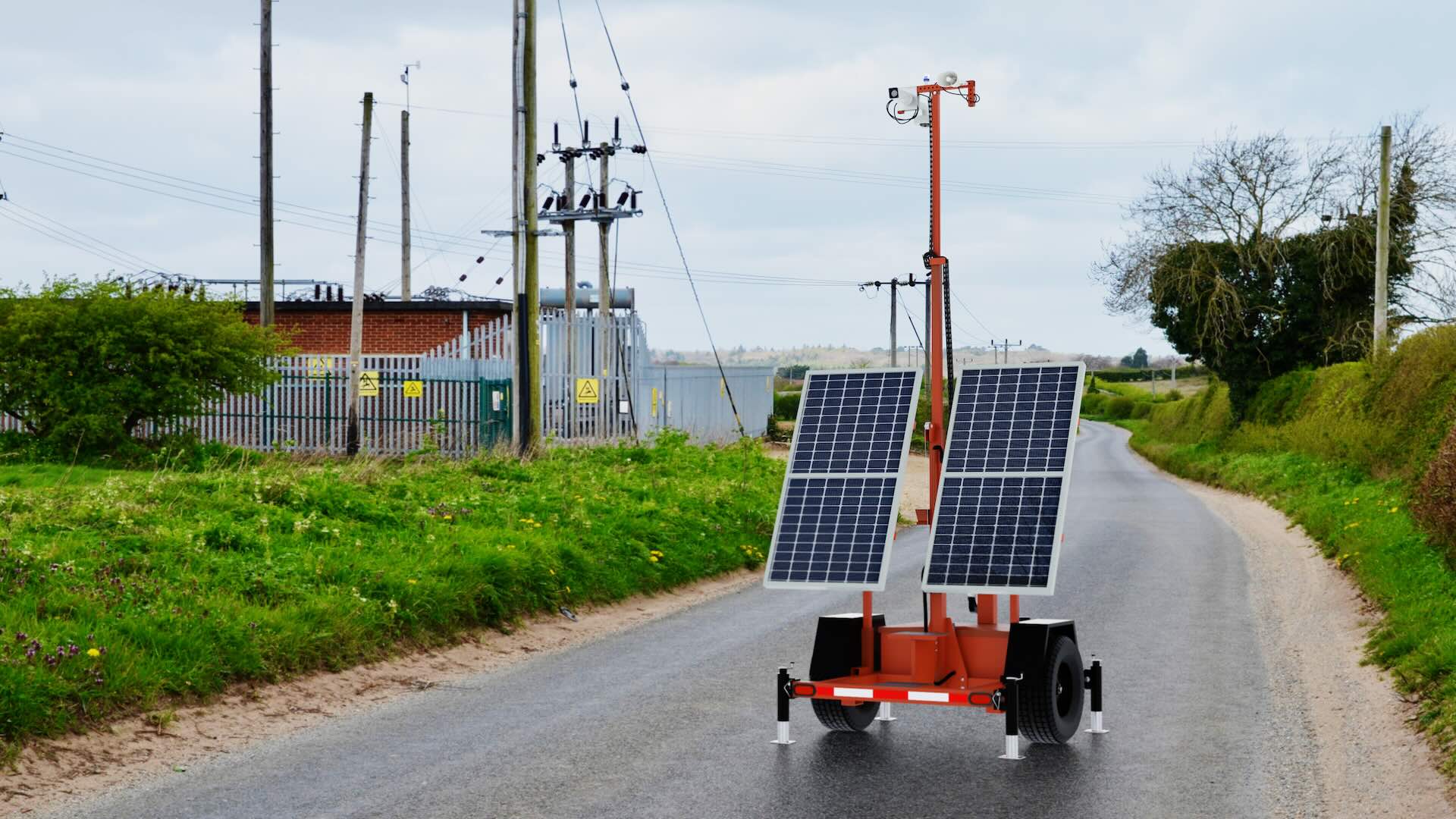 Solar-powered SmartGuard trailer on a rural road near electrical infrastructure.