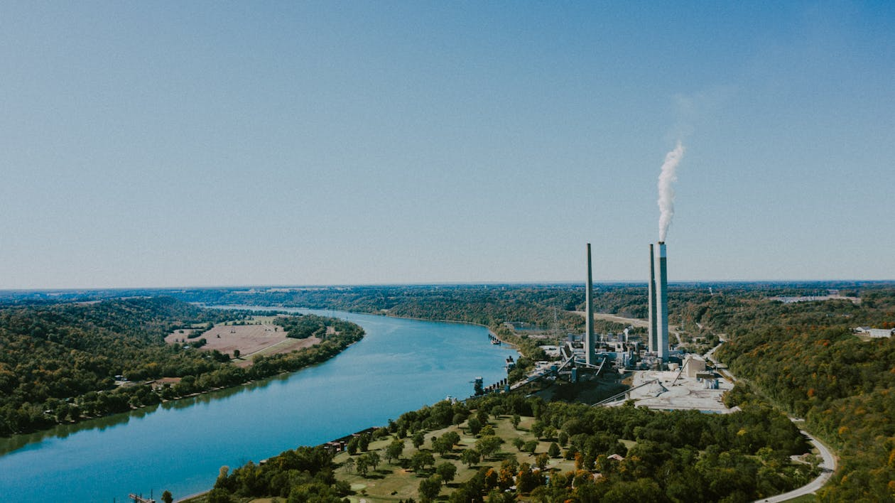 Industrial area located along the edge of a river, with warehouses, infrastructure, and water flowing nearby — illustrating proximity to hydrological risk zones.