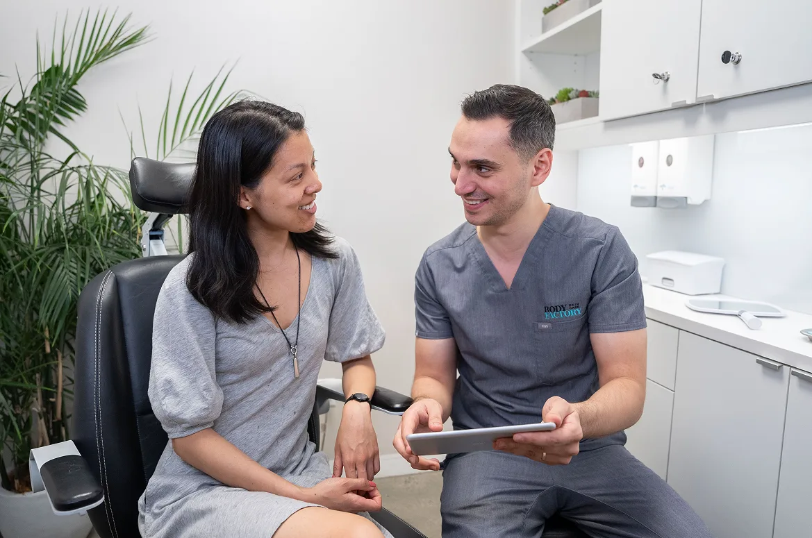 A BodyFactory nurse practitioner reviews a tablet with a patient during her first visit