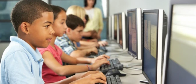 Photograph of a row of focused students working on desktop computers in a school computer lab.