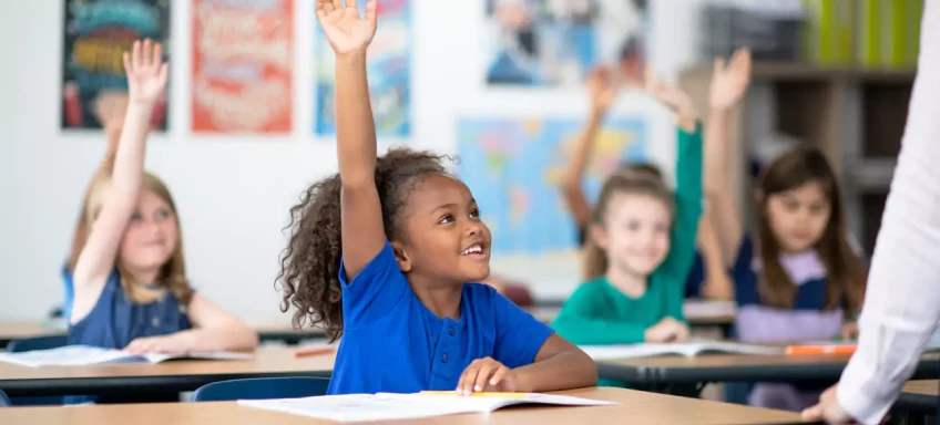 students raising hands in classroom