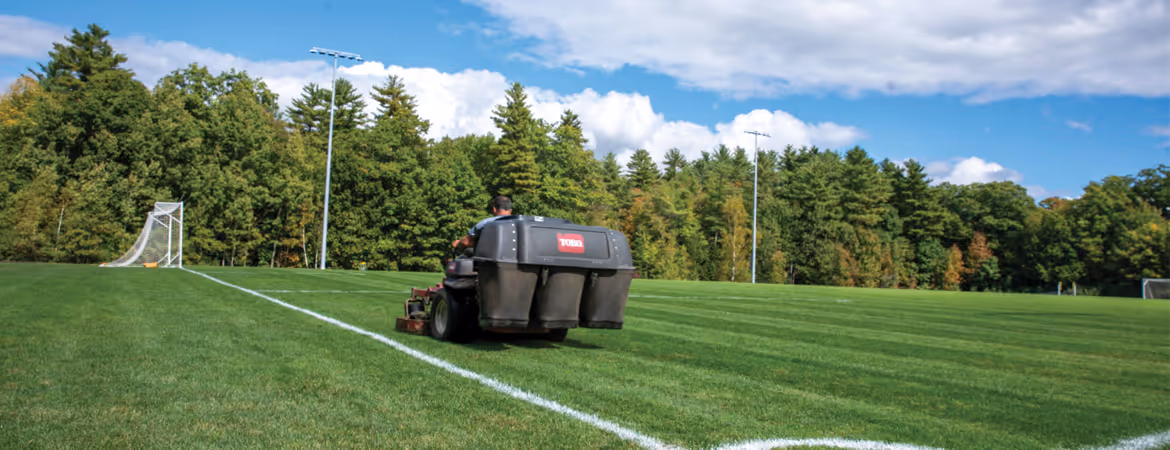 Back view of a riding lawn mower mowing a soccer field