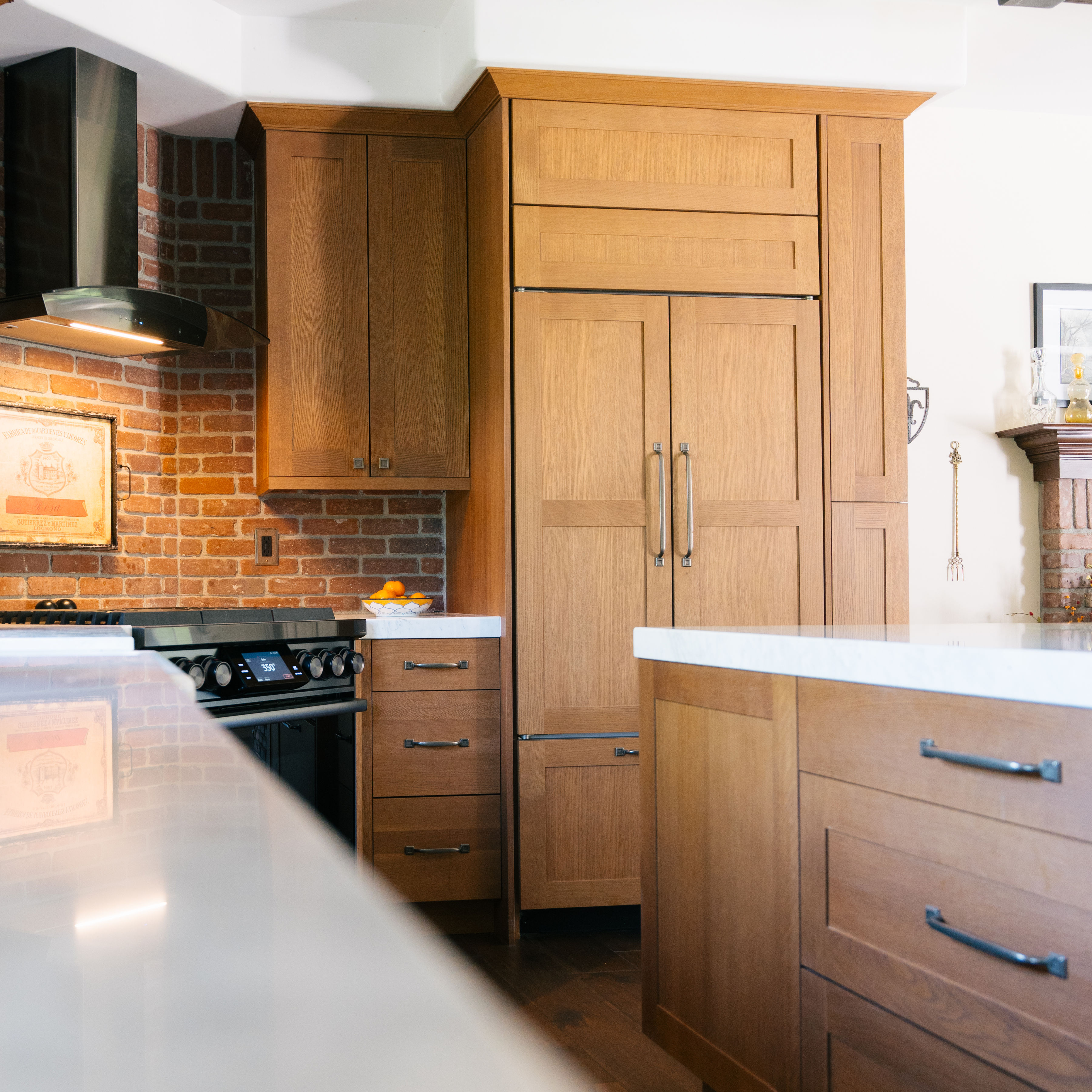 Oak Shaker kitchen cabinetry beside a range and brick backsplash