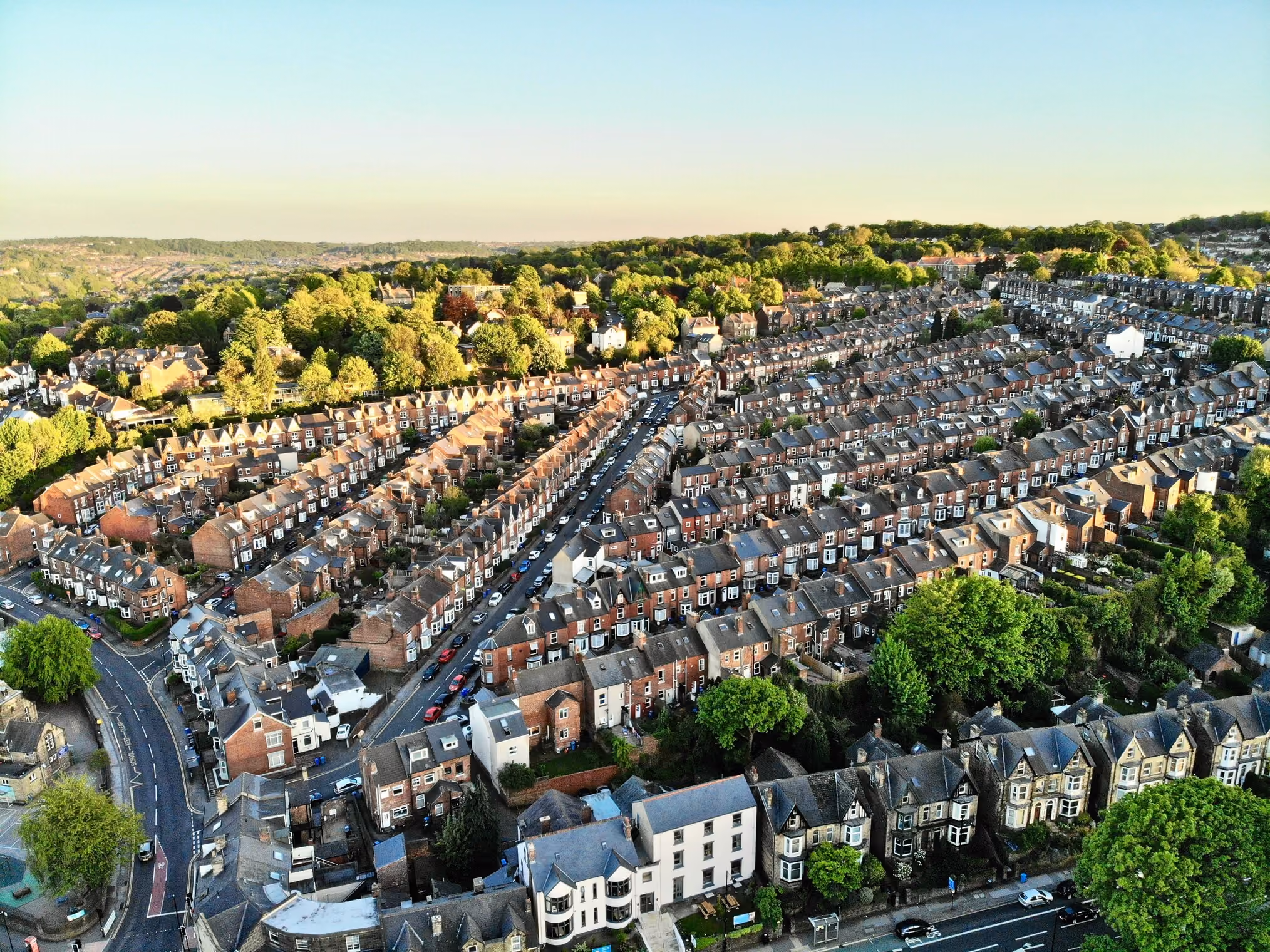 Aerial view of a residential neighborhood with rows of brick houses and green trees.