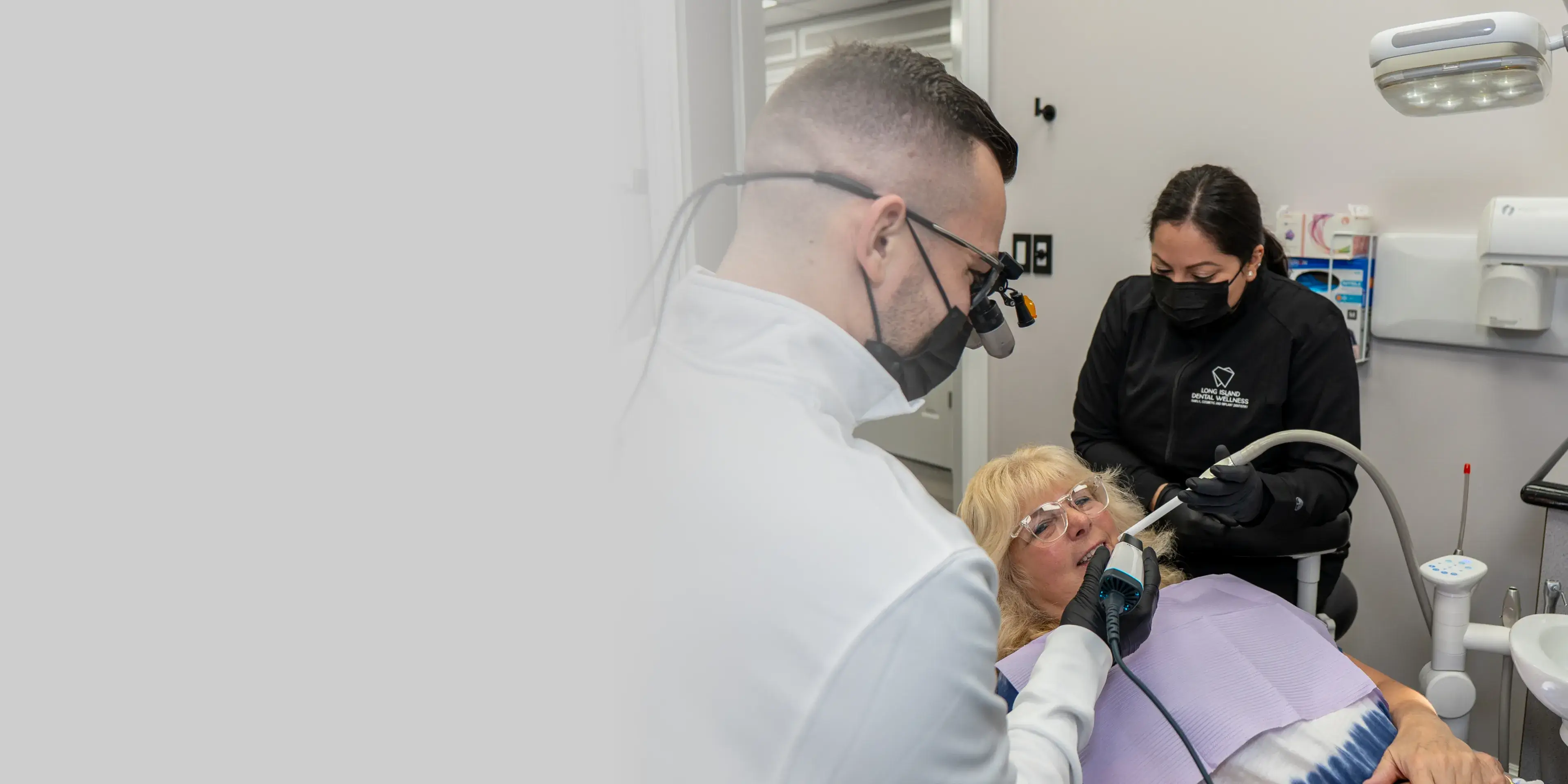 A dentist and assistant perform a dental procedure on a patient in a clinic.
