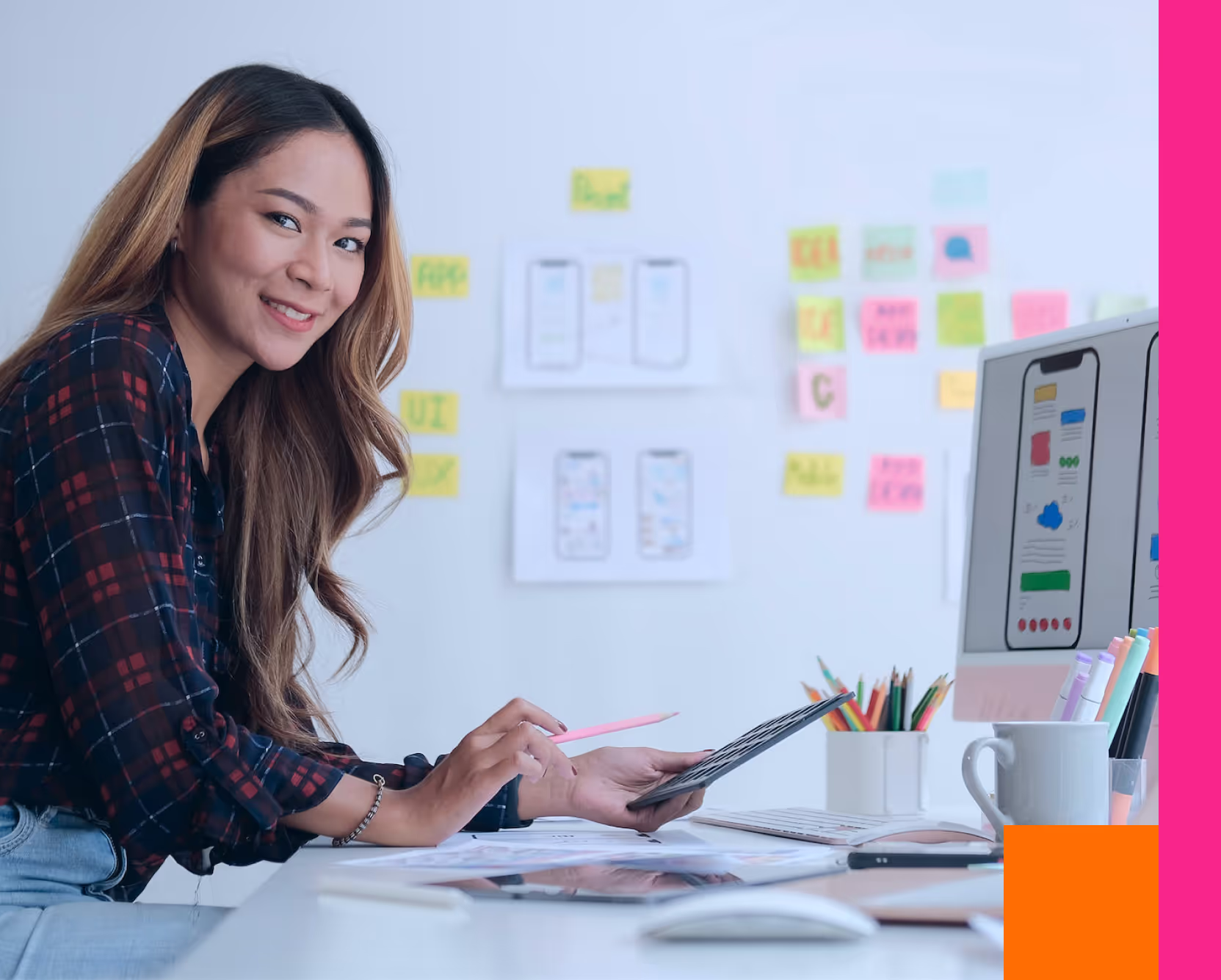 Photo of a happy woman working on a tablet, sitting in a design studio