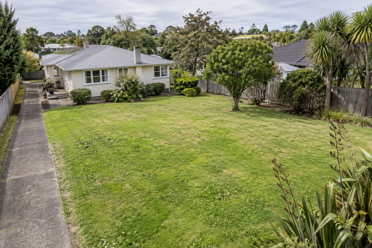 Illustrative home, side driveway and open backyard showing a possible subdivision context.