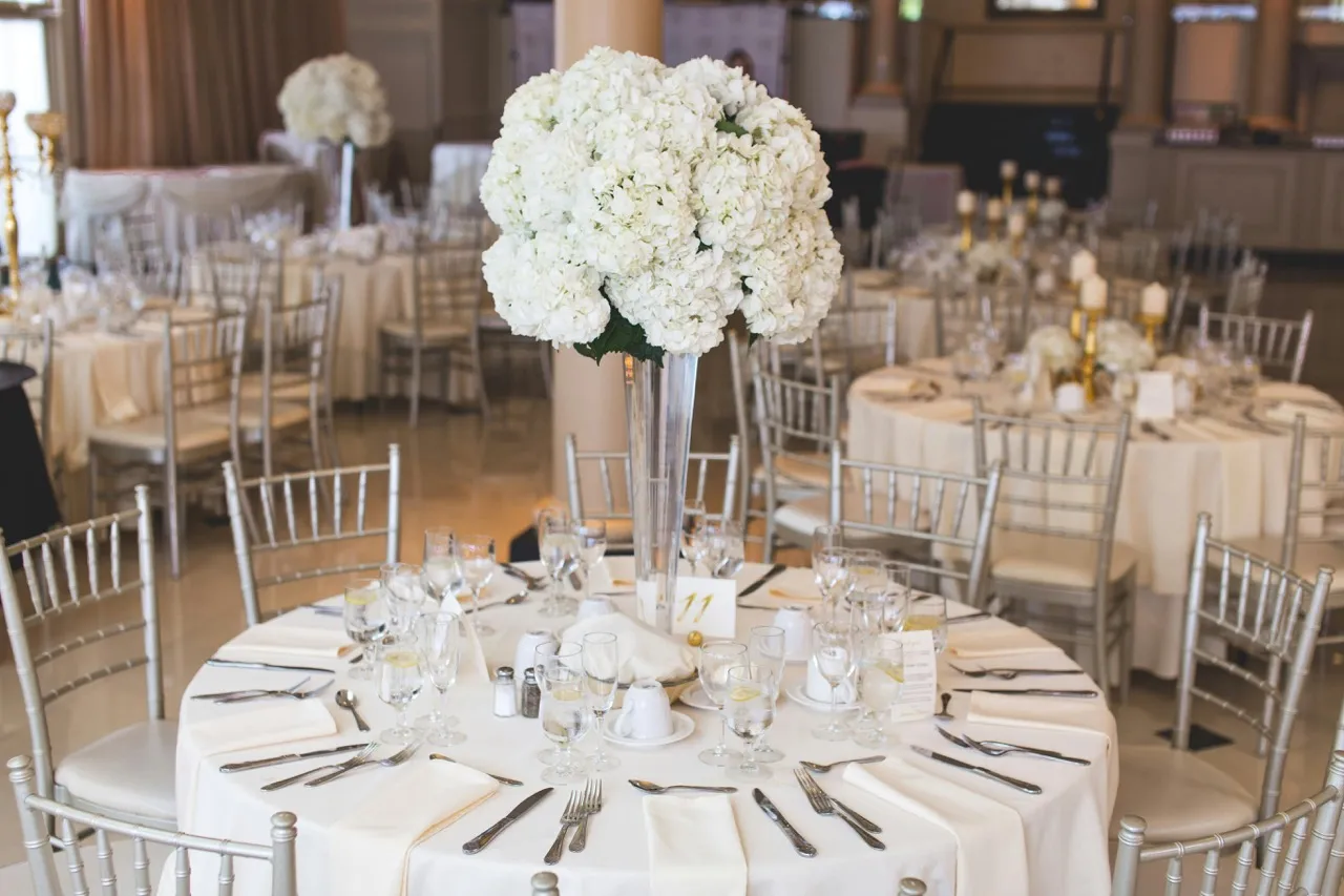 Zarte Tischdeko für Tauffeier mit weißen Blumen, Taufkerze und Kreuz-Details – festlich arrangiert von Babybloom Events