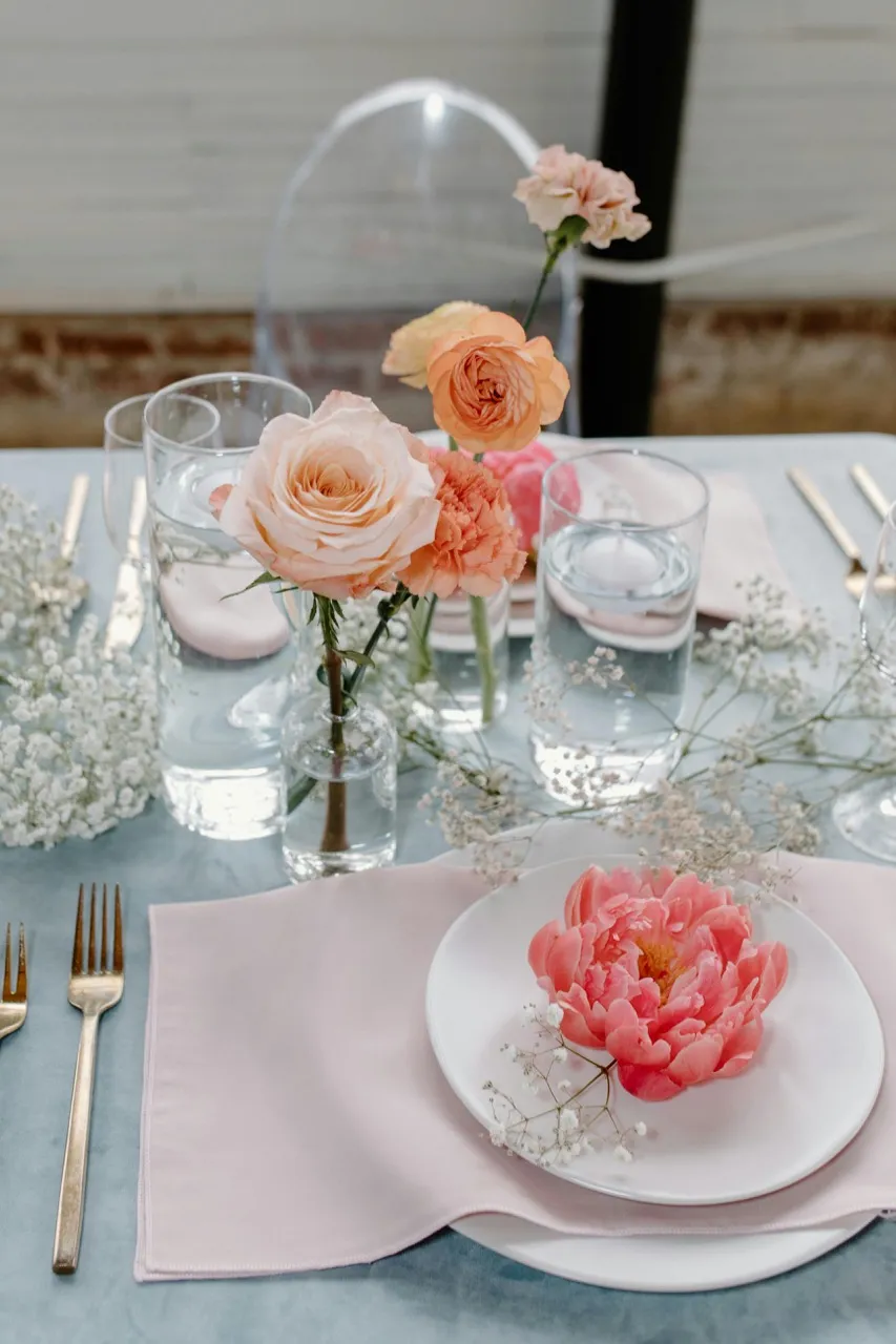 Stilvolle Tischdekoration zur Baby Shower mit Namenskärtchen, Sommerblumen und rosa-orangen Details – gestaltet von Babybloom Wien