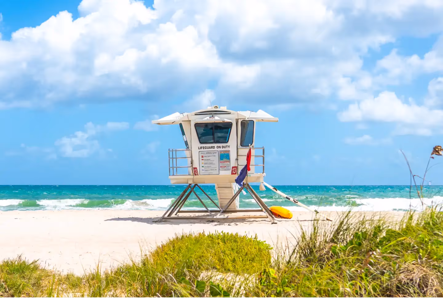 A lifeguard stand on the beach with a surfboard.