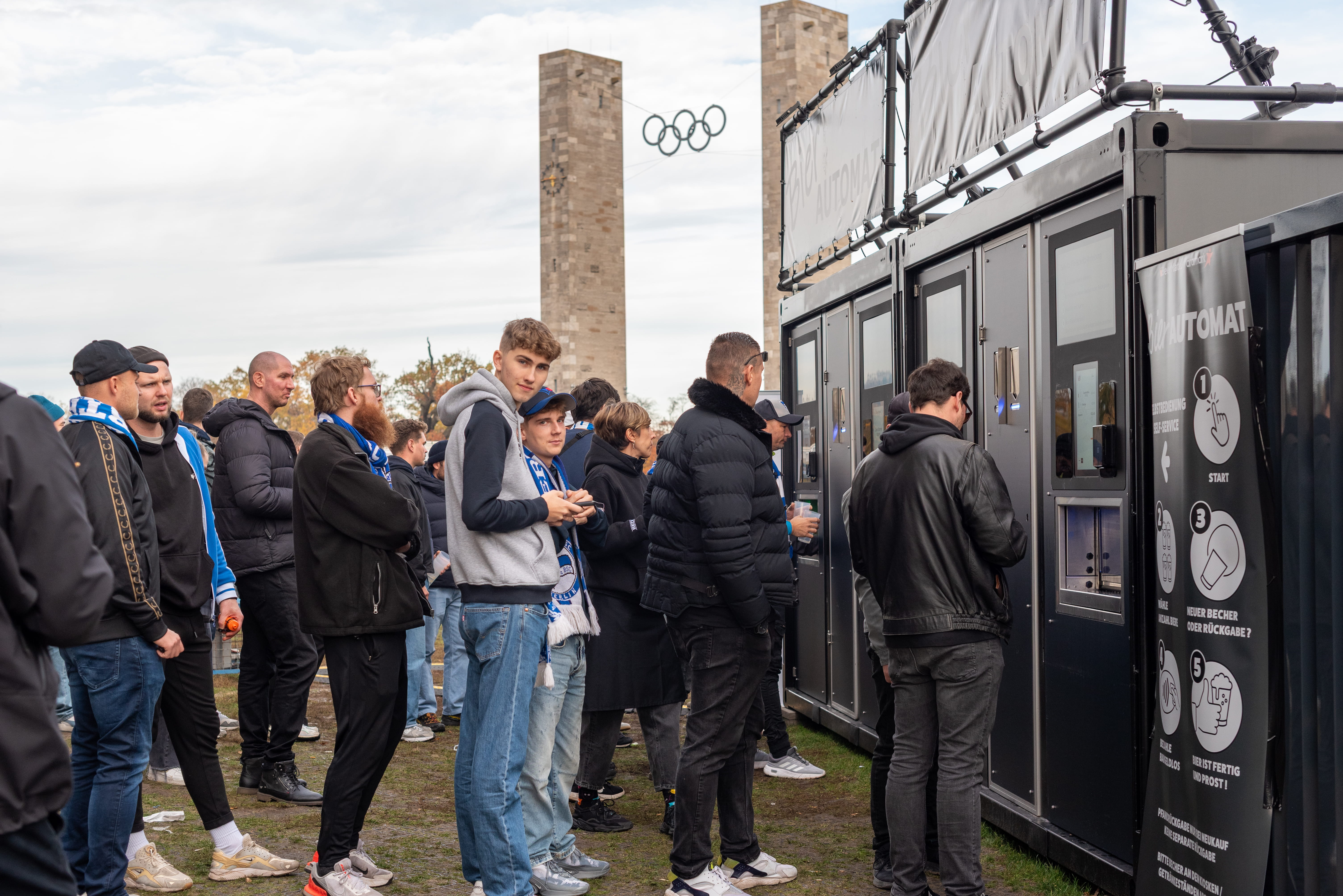 Football fans using BeerMate self-service beer machines outside a stadium before a match.