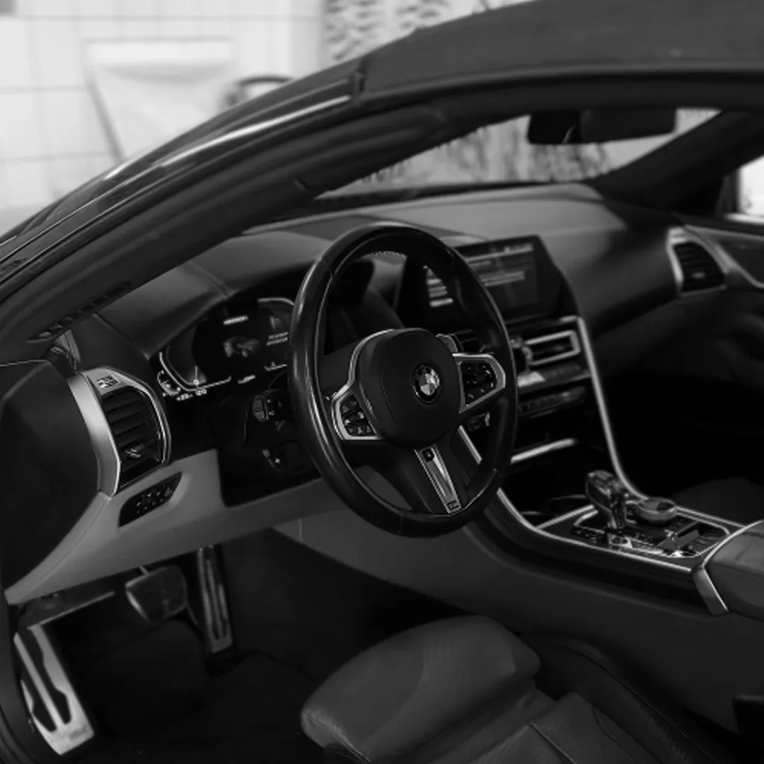 Інтер'єр автомобіля BMW з видимим кермом, панеллю приладів і центральною консоллю.