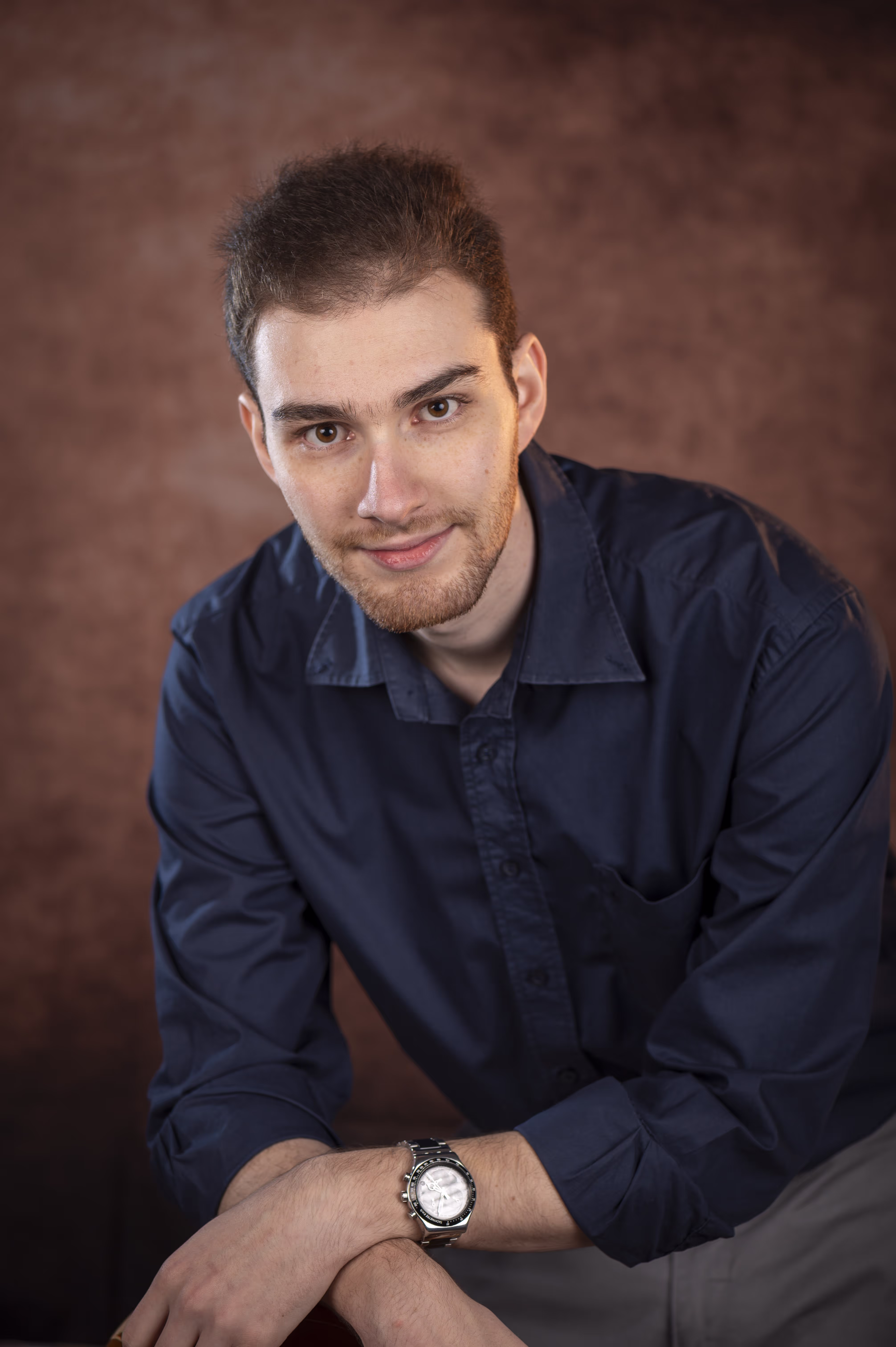 Periklis Kotinis photo in brown background. He wears a blue shirt