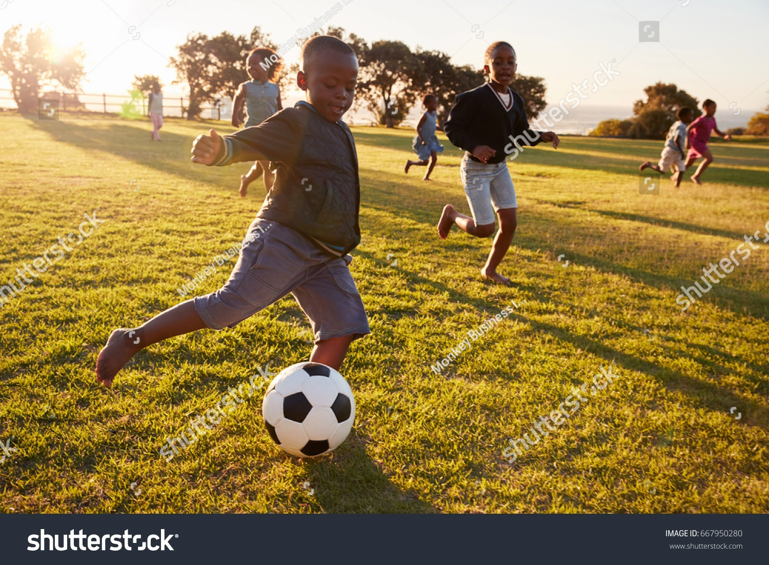 Young kid kicking the ball on a green grass