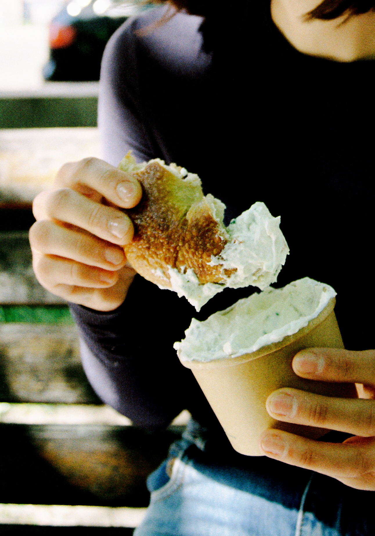 A feshly baked bagel being dipped in sauce.