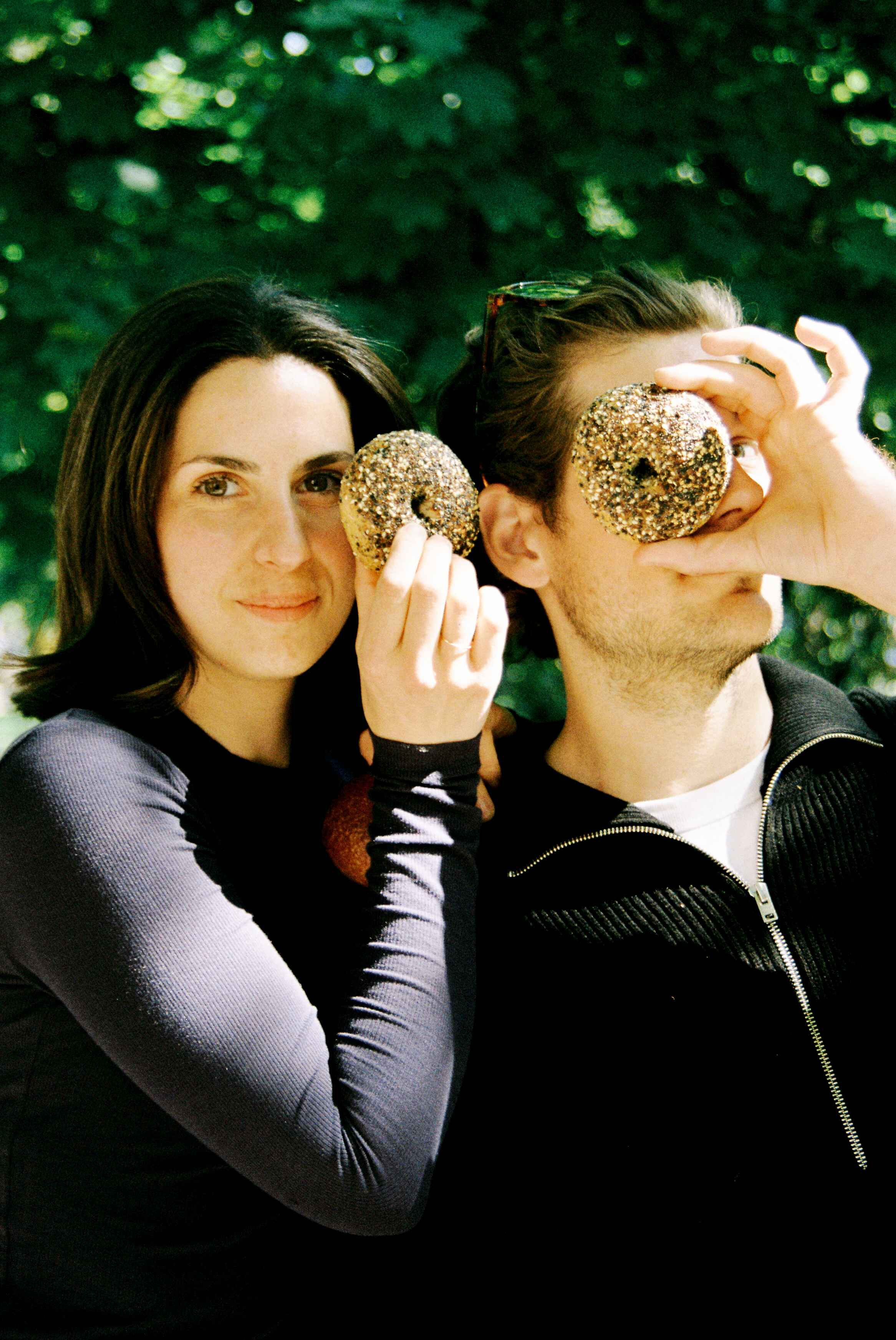 Two friends hold up freshly baked bagels. 