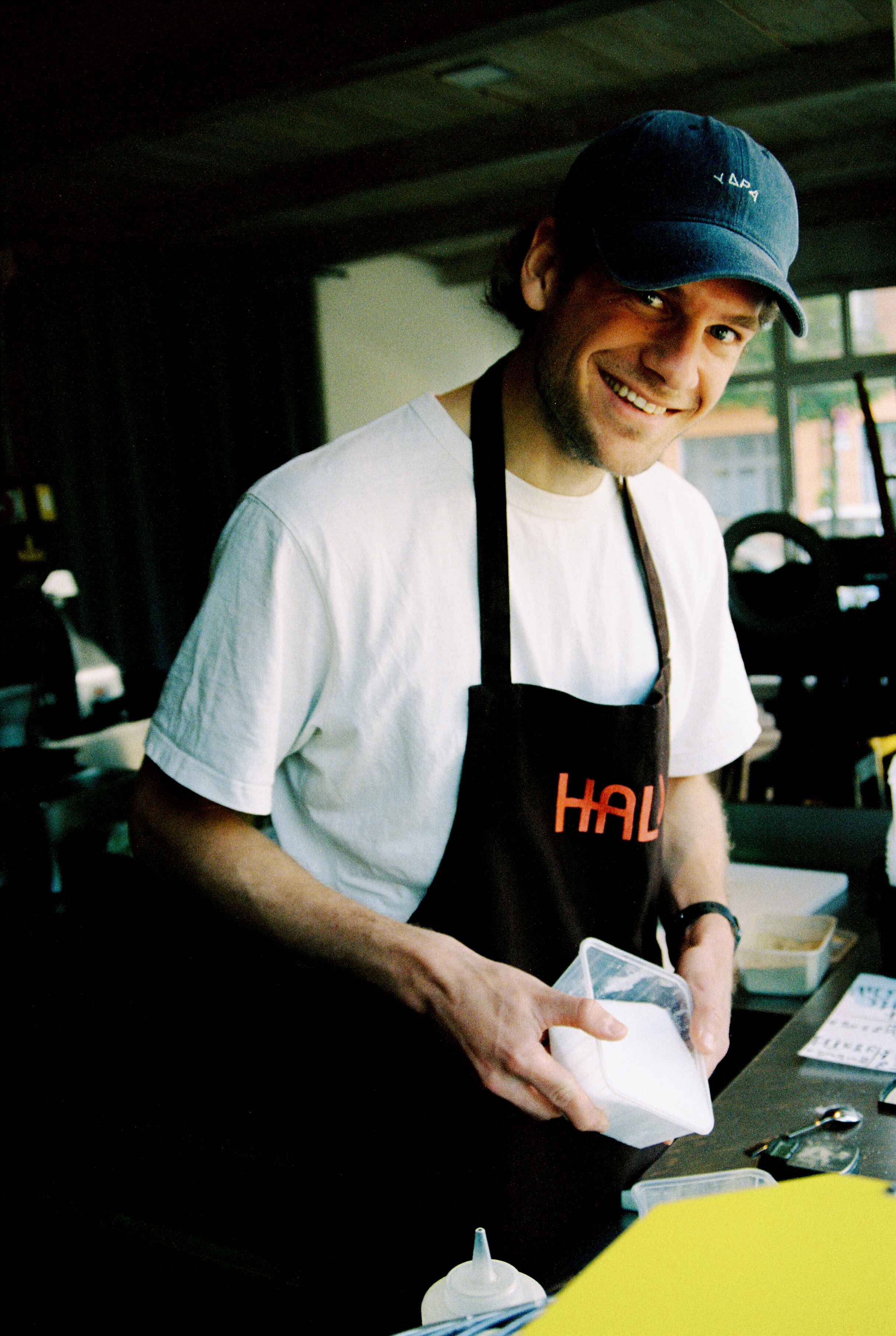 A baker smiling at the camera while making bagels. 