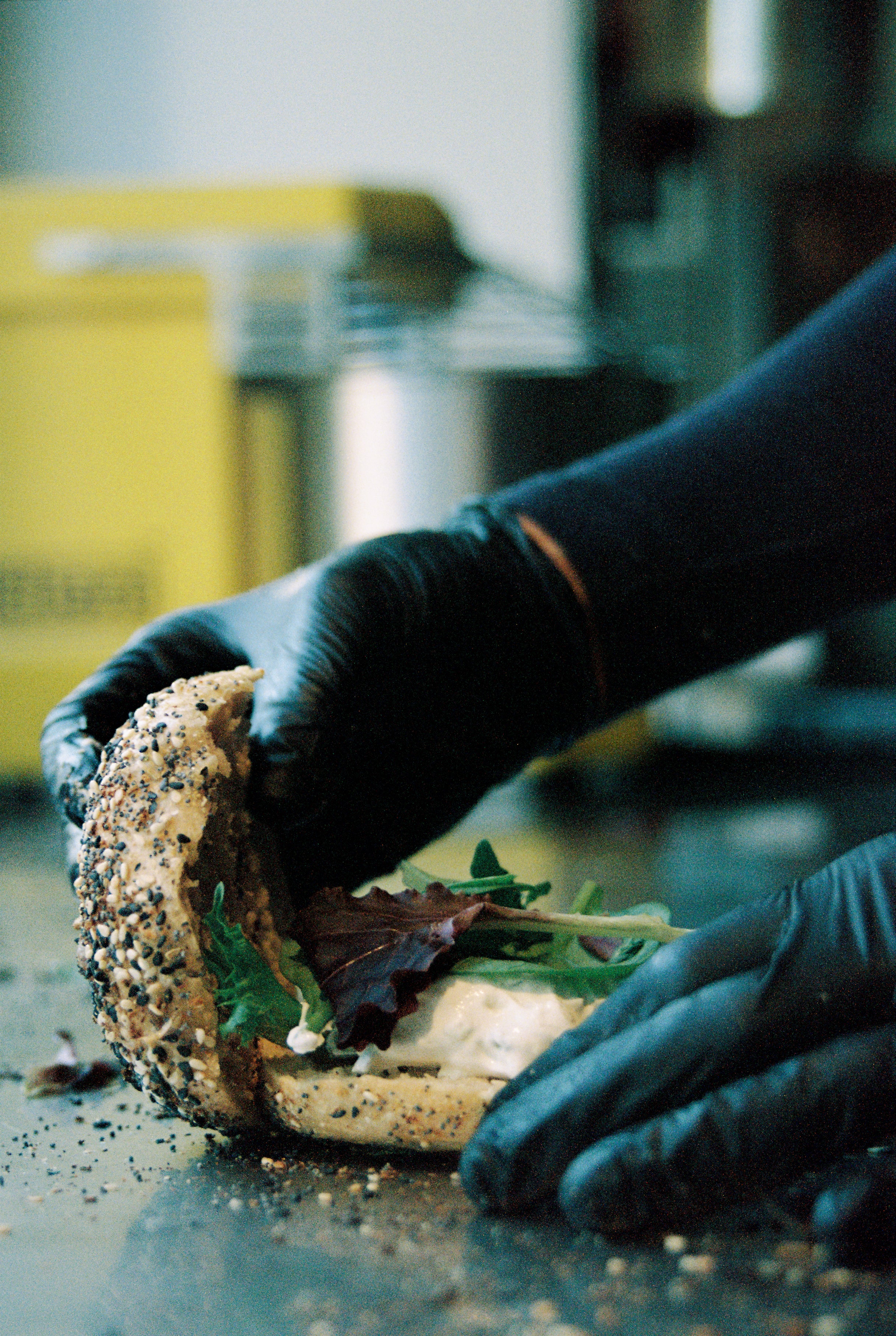 A freshly baked bagel being prepared with fresh ingredients.