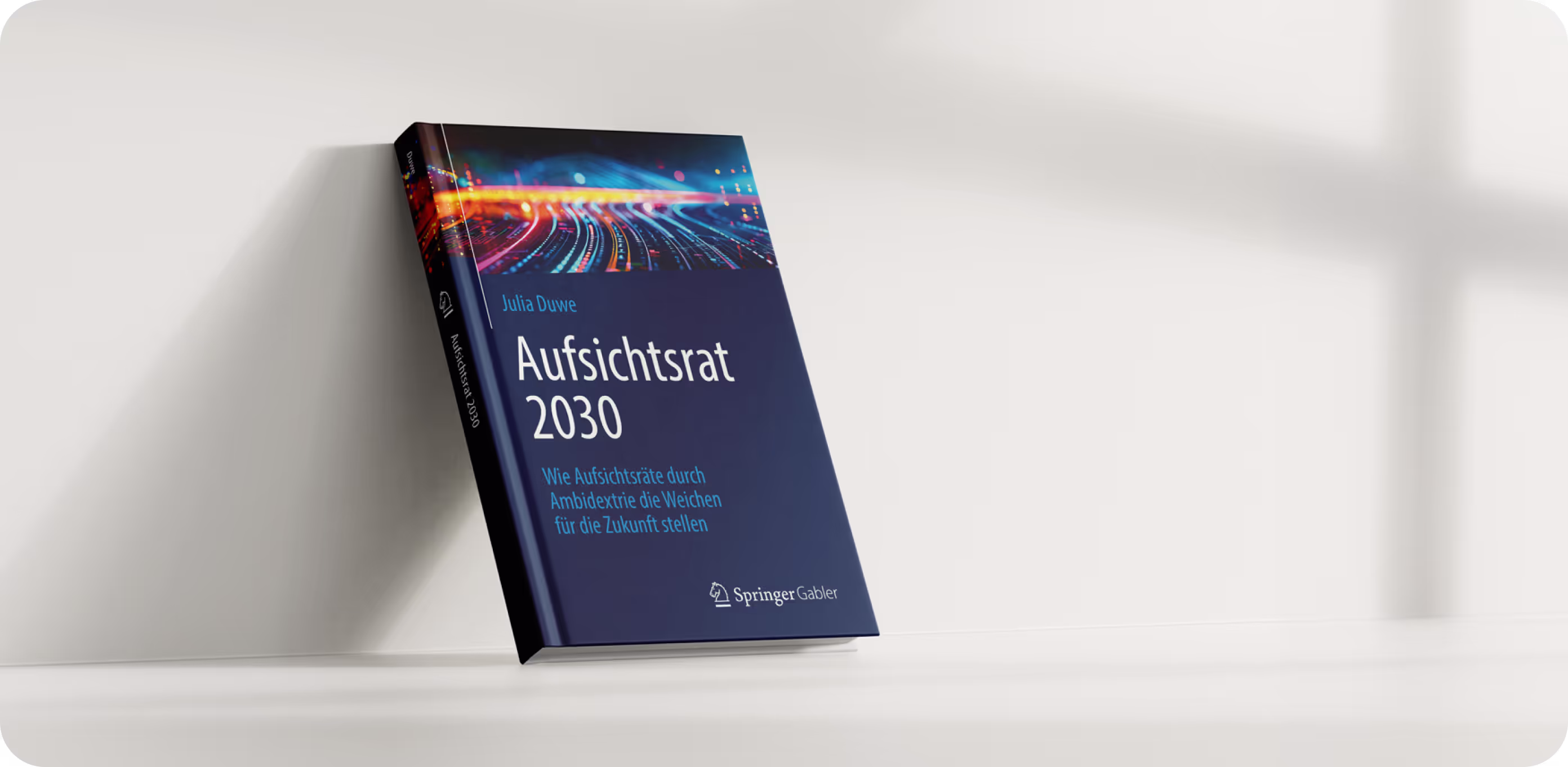 Ein blaues Buch mit dem Titel "Aufsichtsrat 2030" von Dr. Julia Duwe lehnt an einer weißen Wand
