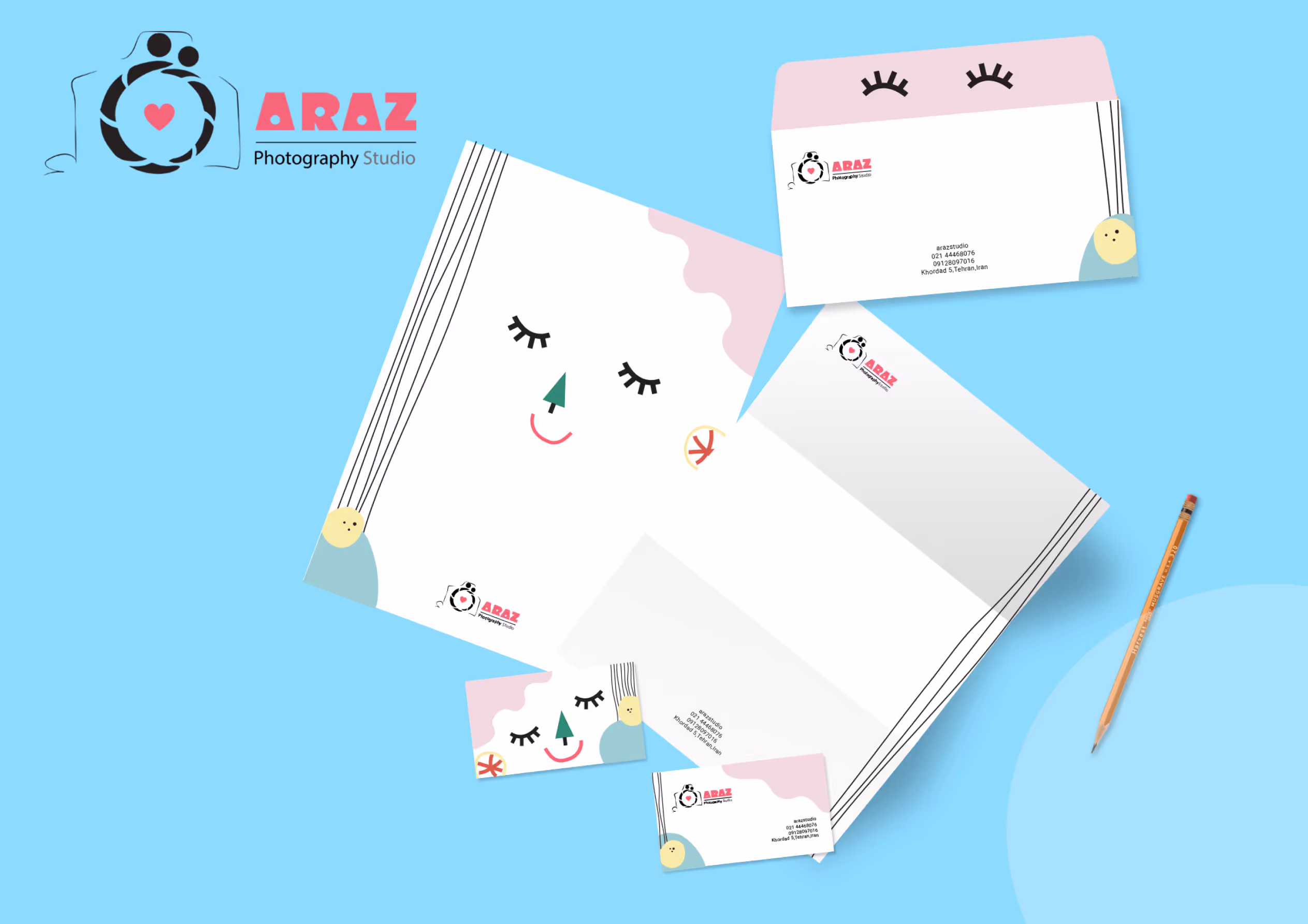 Schreibwarenset für das Araz Photography Studio auf blauem Hintergrund. Enthält Briefkopf, Umschlag und Visitenkarte mit verspielten, lächelnden Gesichtsillustrationen und dem Logo des Studios mit einer Kamera und einem Herz.