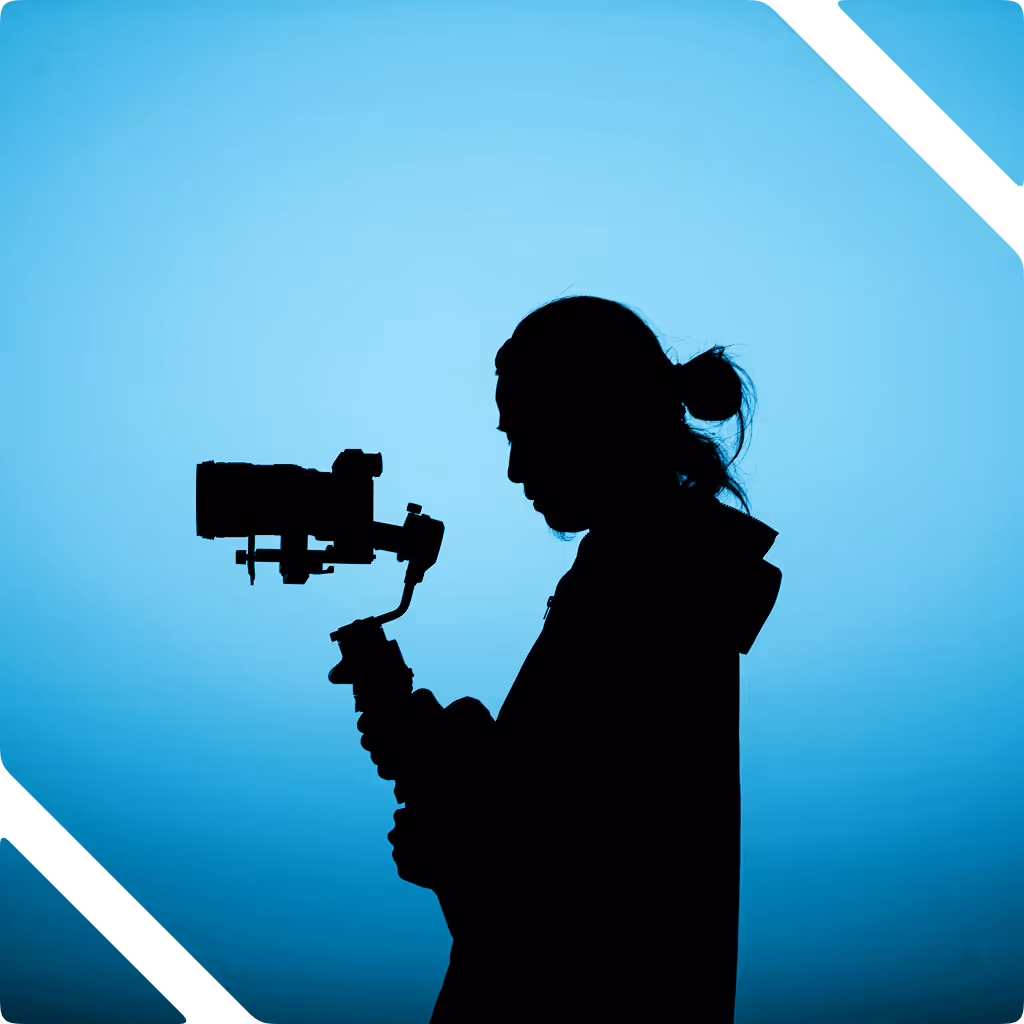 Silhouette of a person with a bun holding a camera on a stabilizer against a blue background.