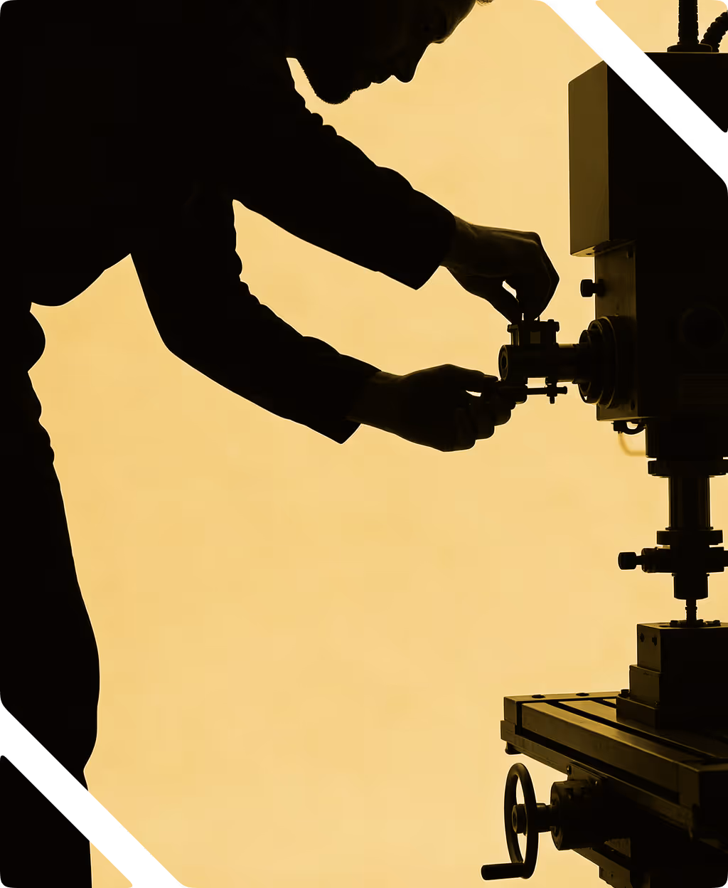 Silhouette of person adjusting a mechanical part on an industrial machine against yellow background.