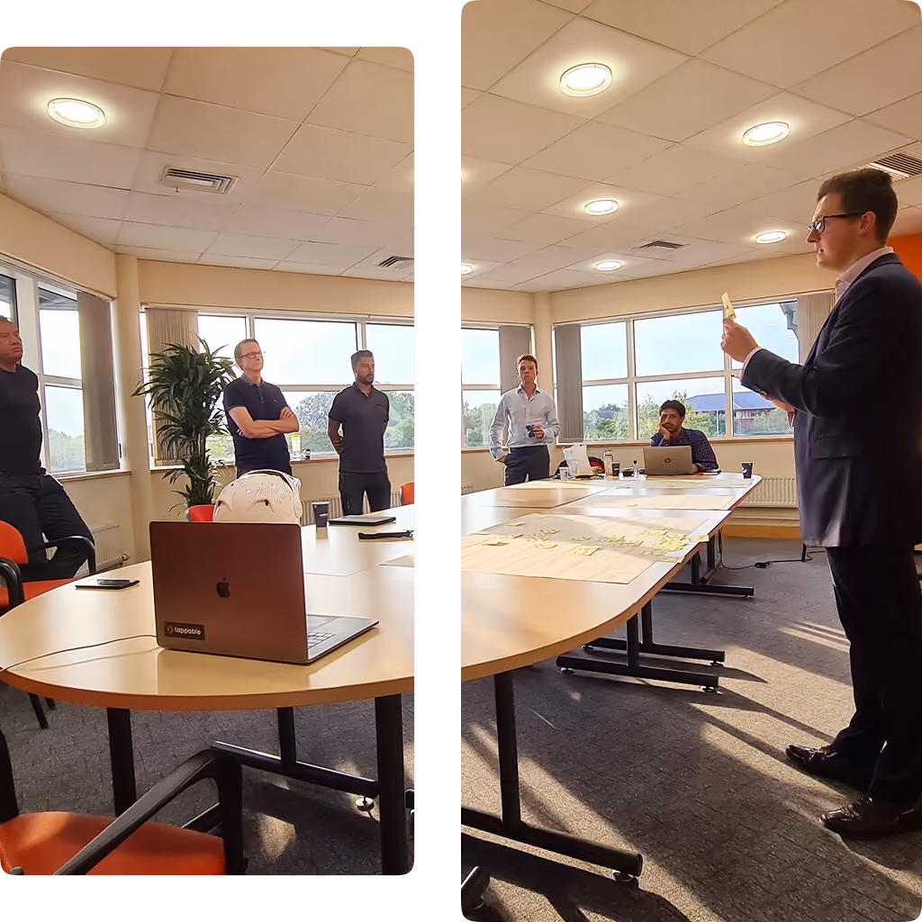 Group of five professionals in a meeting room with a laptop and sticky notes on the table.