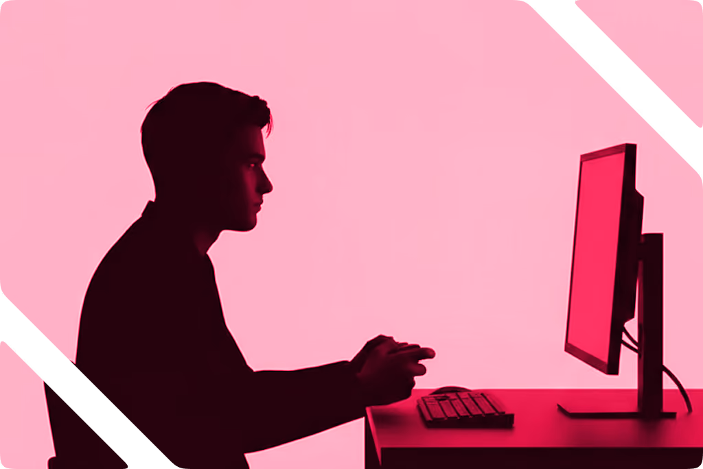 Silhouette of a man sitting at a desk using a computer with a pink background.