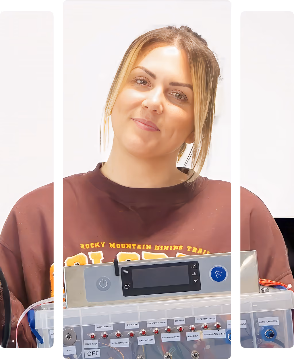 Smiling woman holding an electronic device with display and labeled switches on front panel.