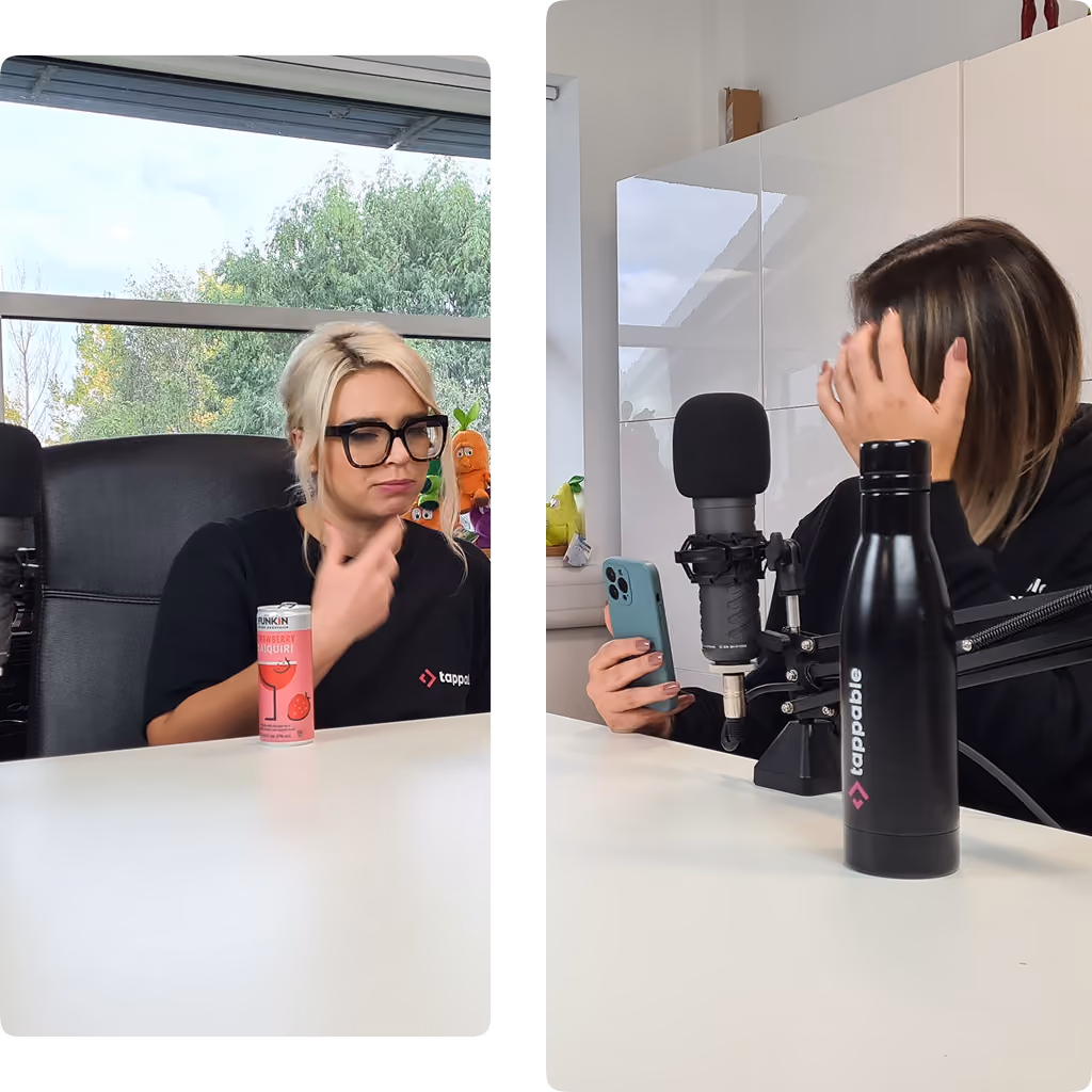Two women in podcast studio, one with phone and black tappable bottle, the other with drink can.