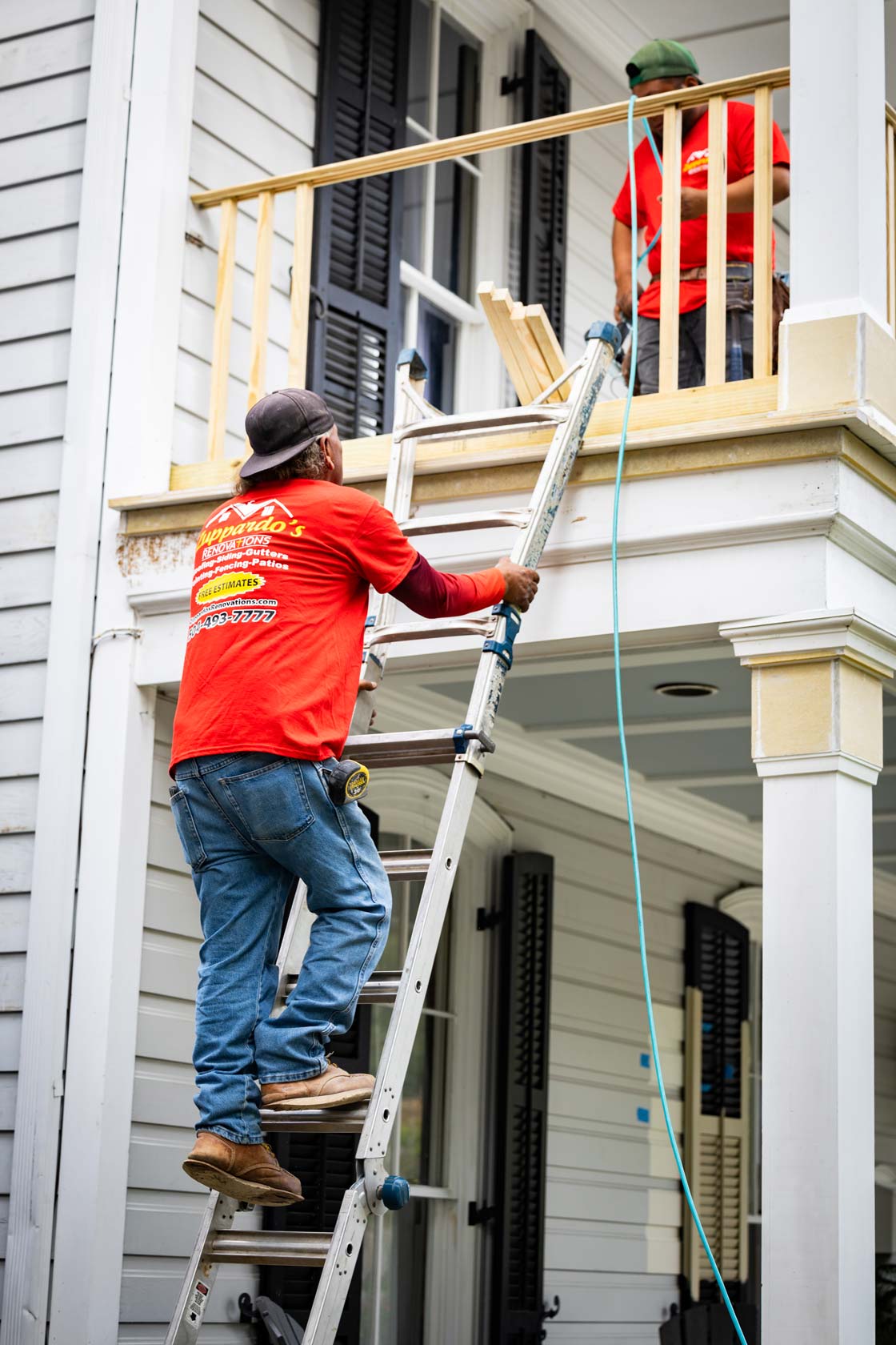 Man with Zuppardo's Renovations t-shirt climbing on ladder to second story balcony