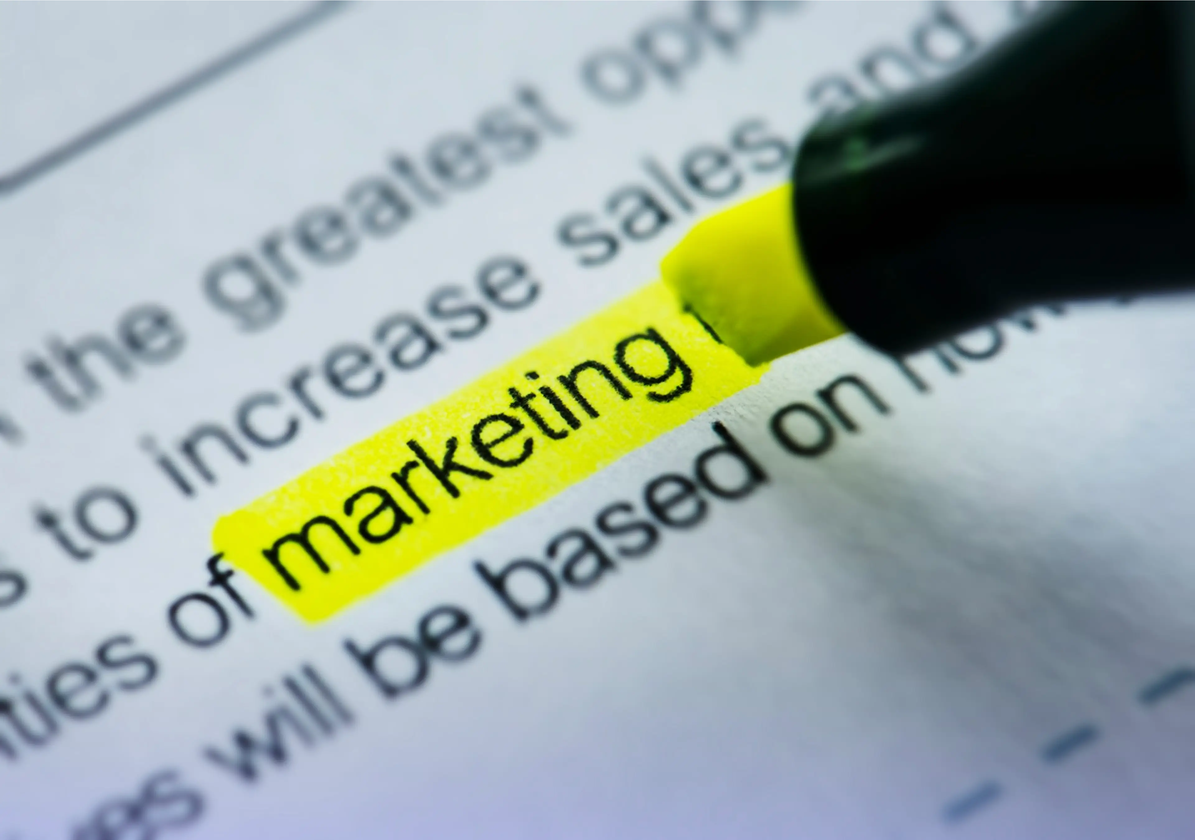 Close-up of the word "marketing" highlighted in yellow on a printed document