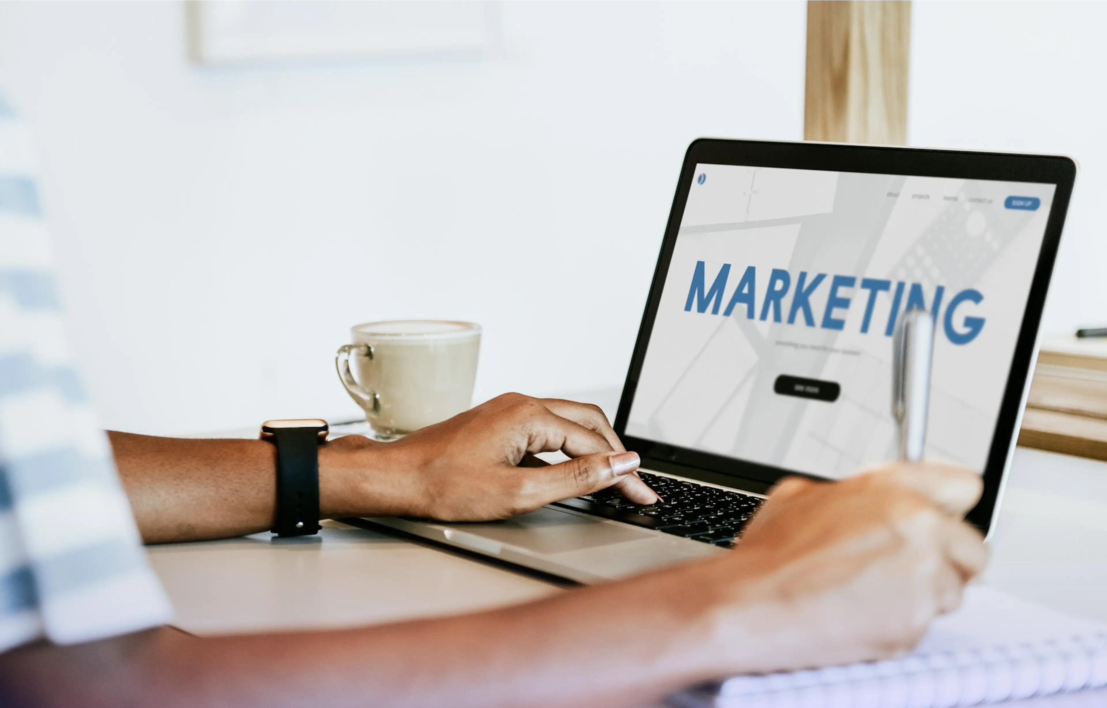 Person working on a laptop displaying the word "MARKETING" on the screen