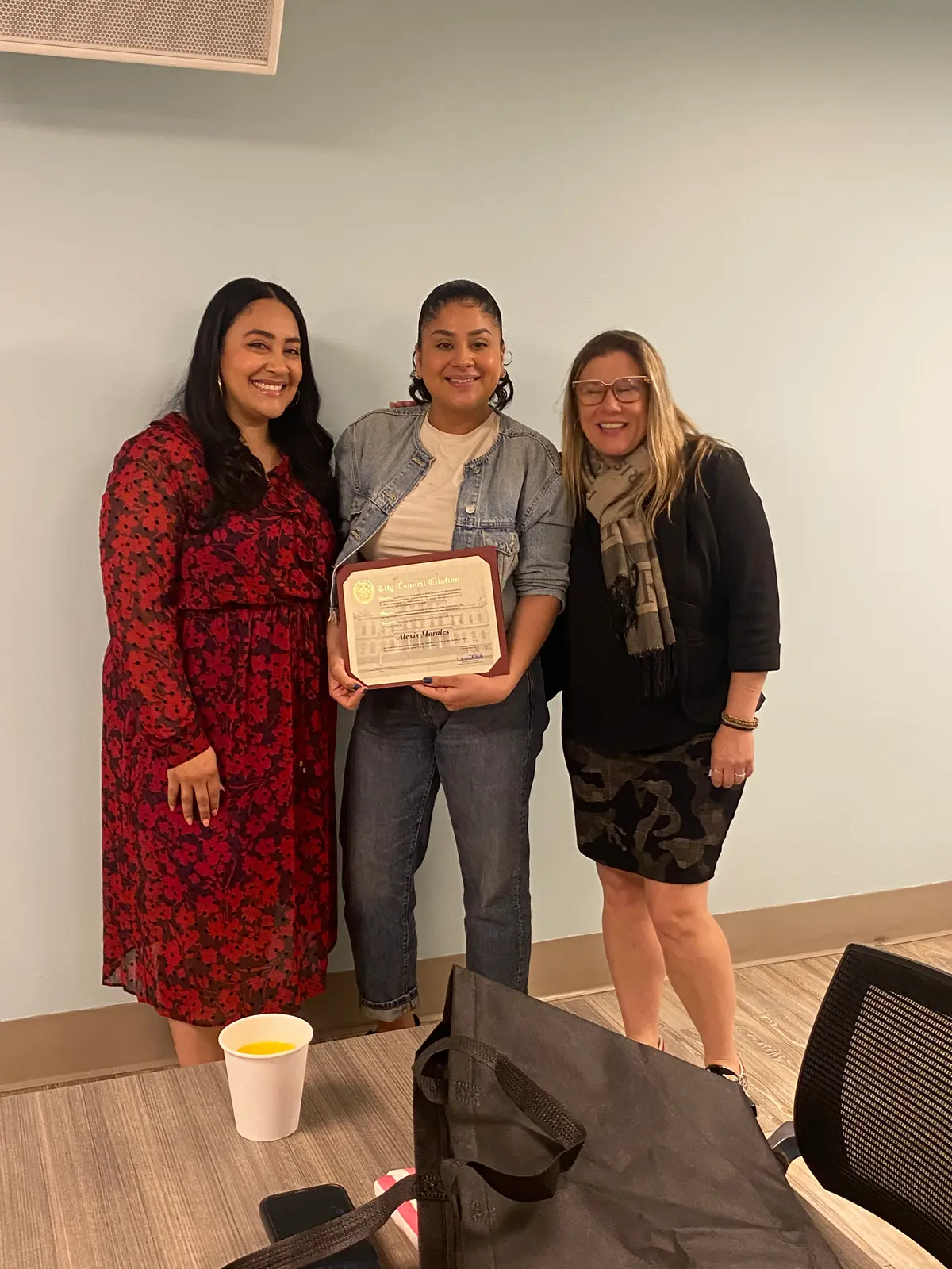Student receiving City Council citation award flanked by two women
