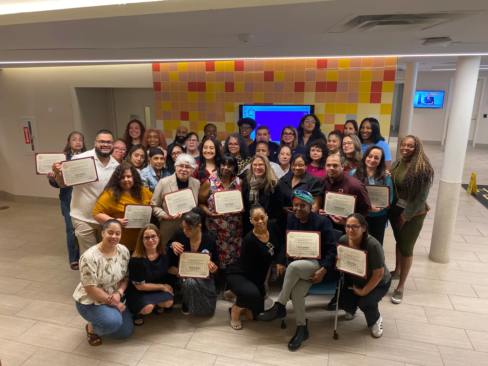 Large group of staff members posing with certificates at ceremony